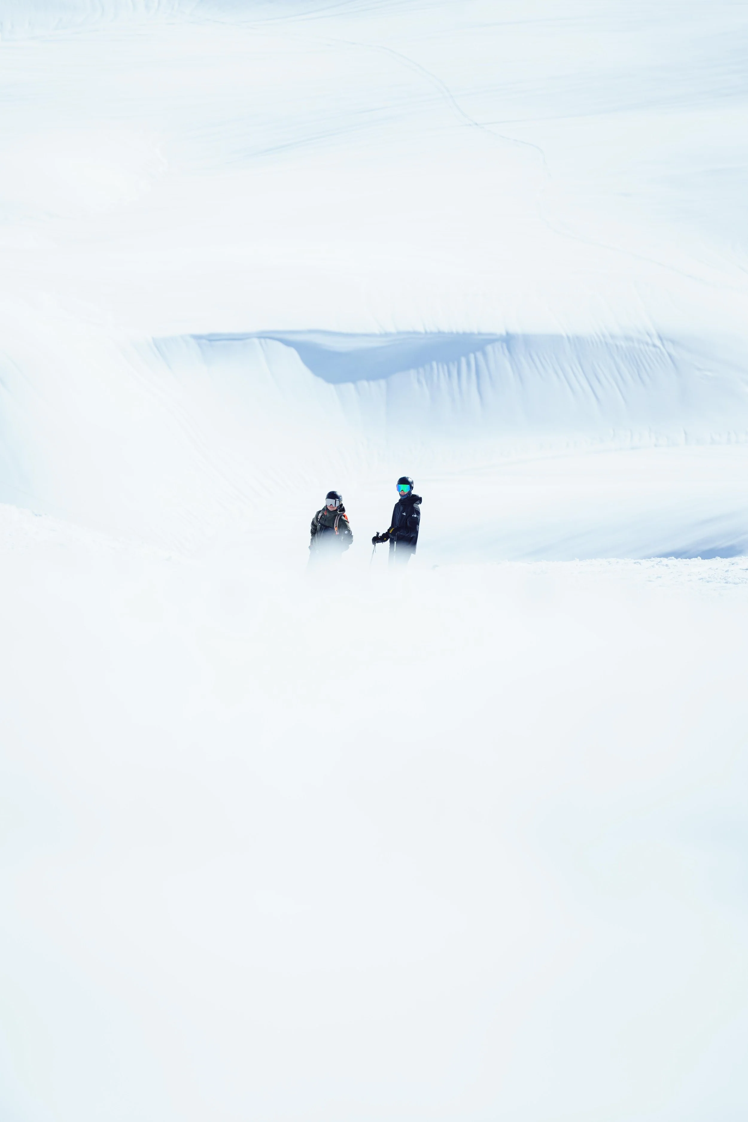 Deux skieurs sur une pente enneigée avec un ciel bleu en arrière-plan.