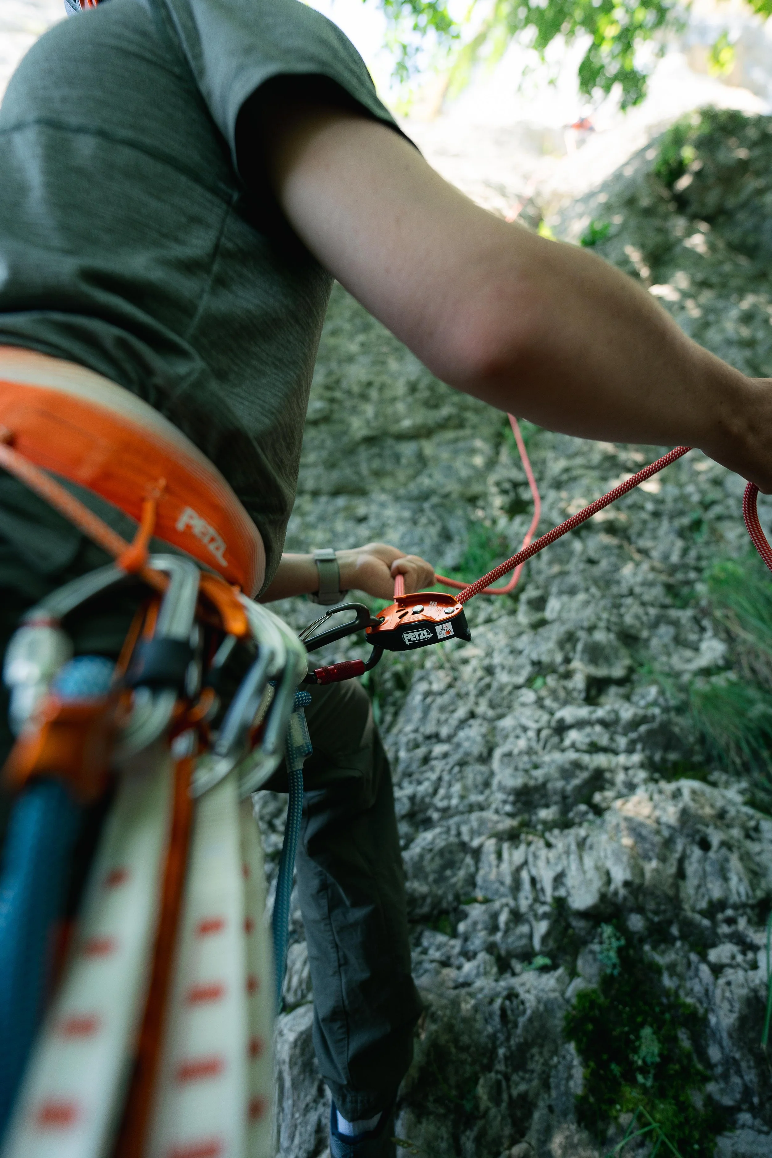 Personne en train de faire de l'escalade, montrant un harnais et un système d'assurage sur une paroi rocheuse.