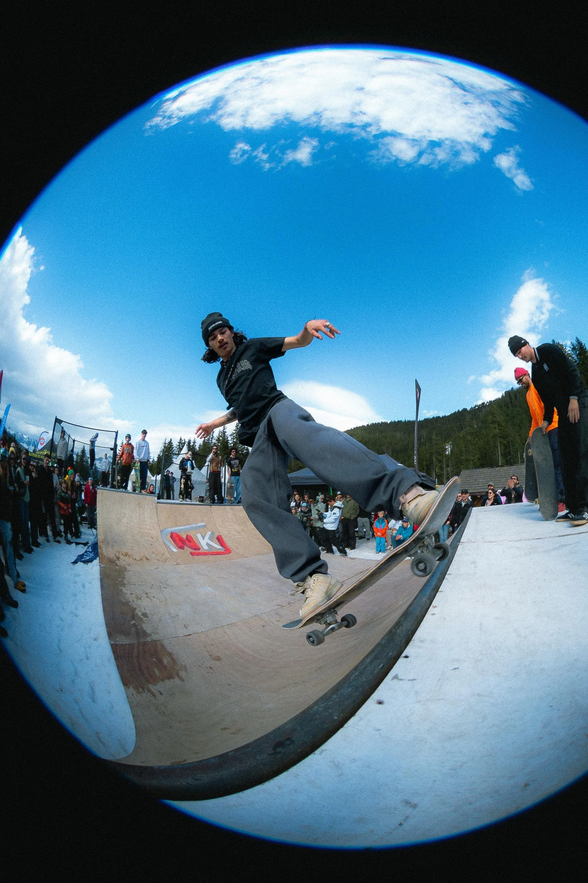 Skateur en plein mouvement sur une rampe avec un public en arrière-plan.