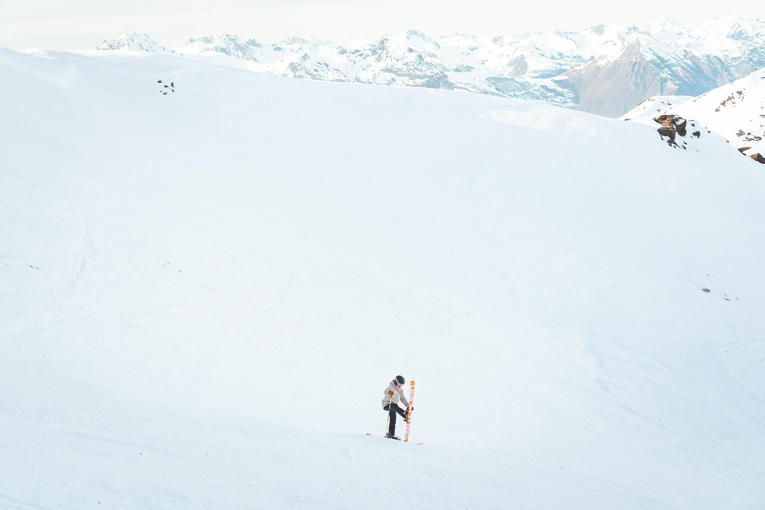 Une personne seule sur une pente enneigée avec un paysage de montagnes en arrière-plan.