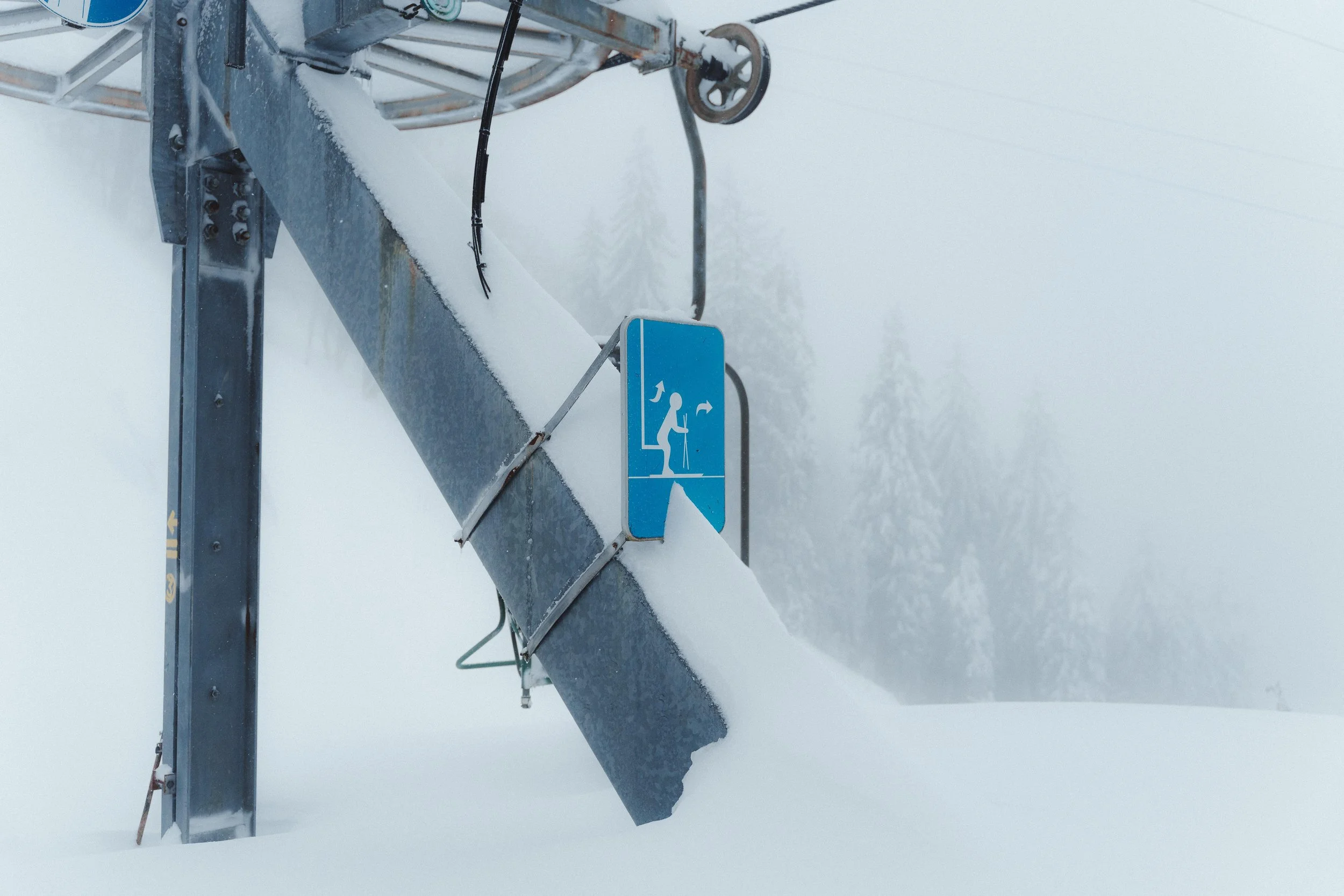 Panneau d'avertissement bleu pour le ski, neige, pylône, arbre enneigé en arrière-plan.