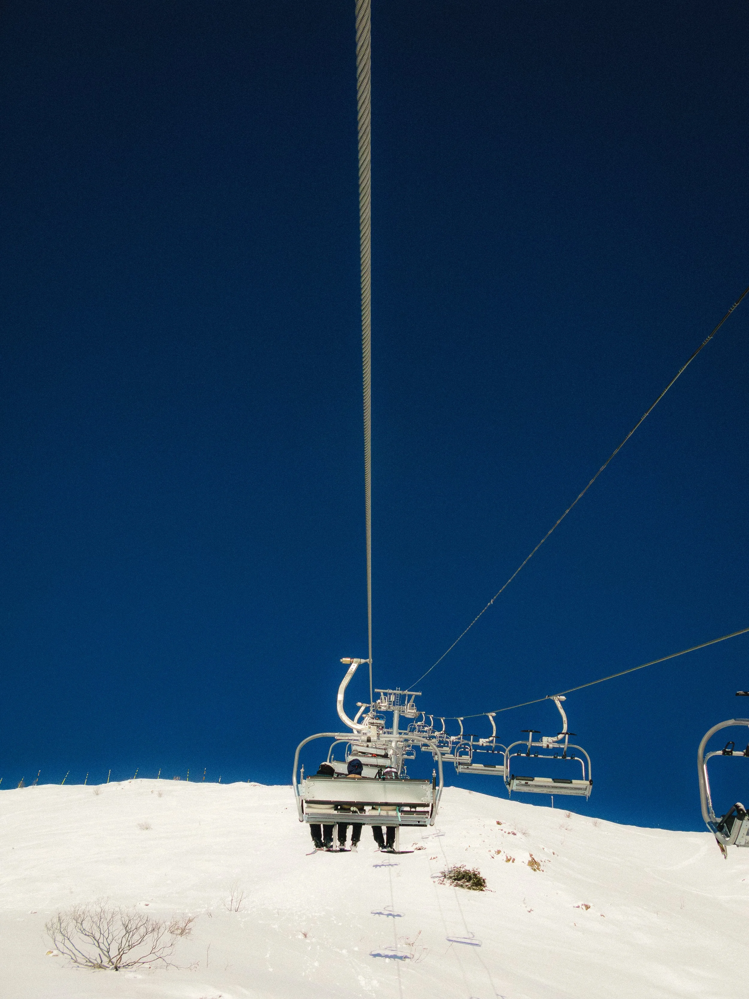 Télésiège sur une station de ski enneigée sous un ciel bleu.