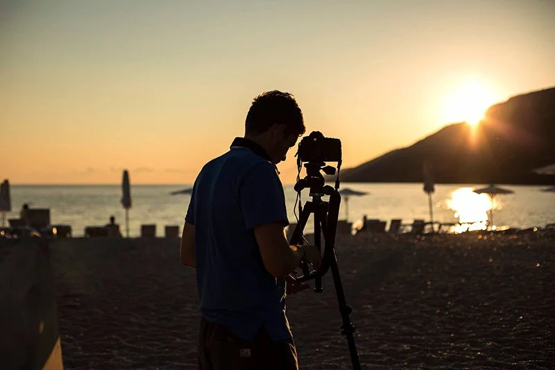 silhouette of man using camera at sunset on a beach
