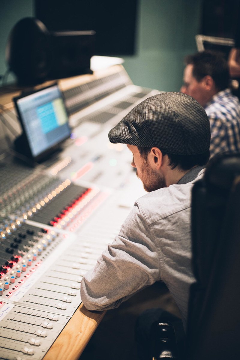 man sat at audio mixing desk