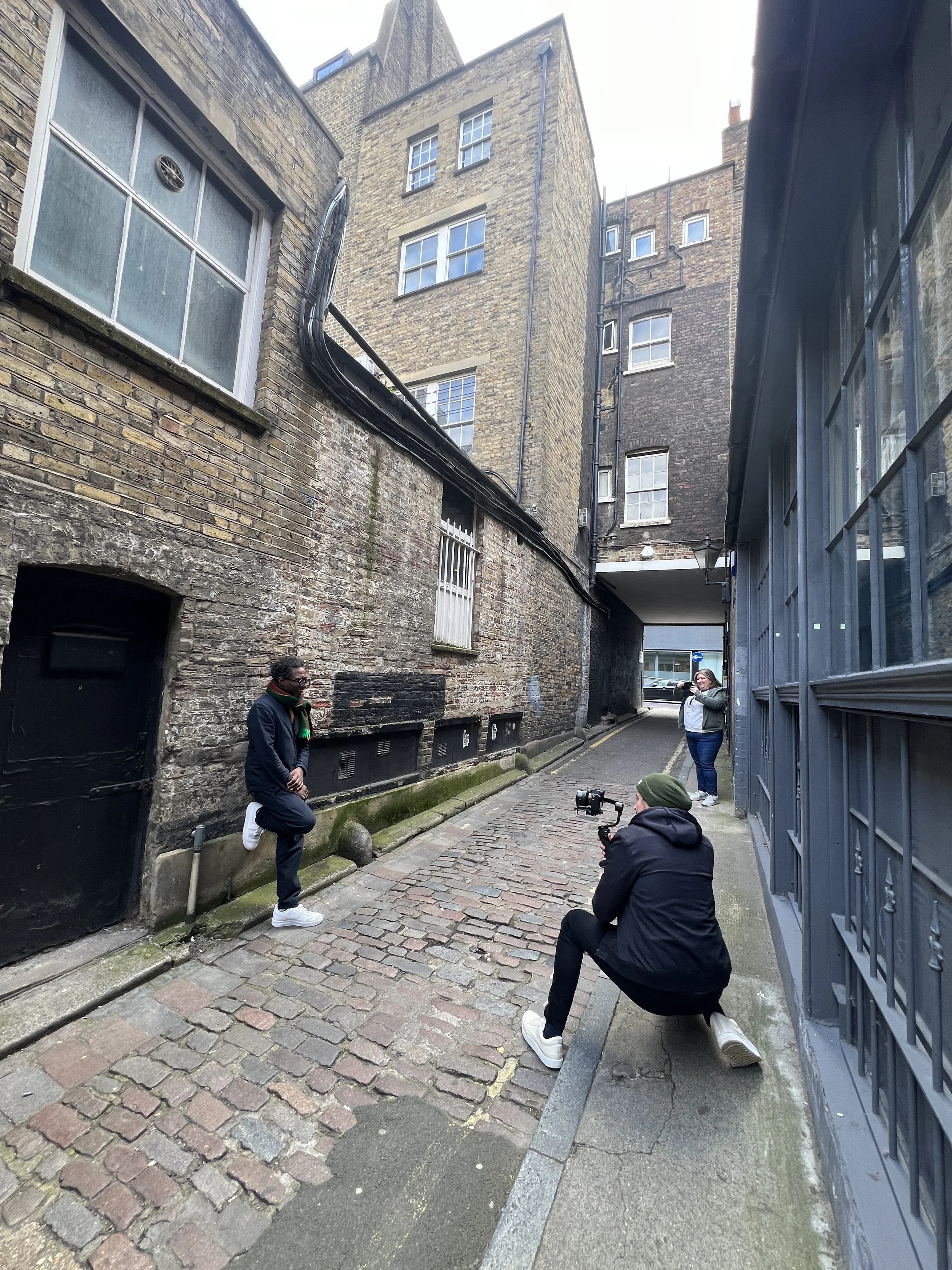man taking photograph of man relaxing against wall in alleyway