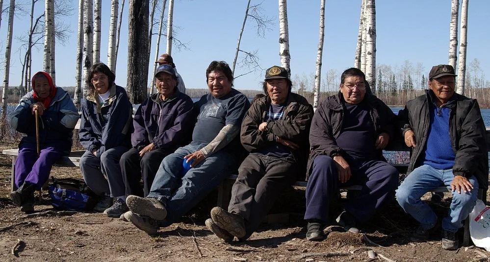 A group of Indigenous elders sitting on a bench.