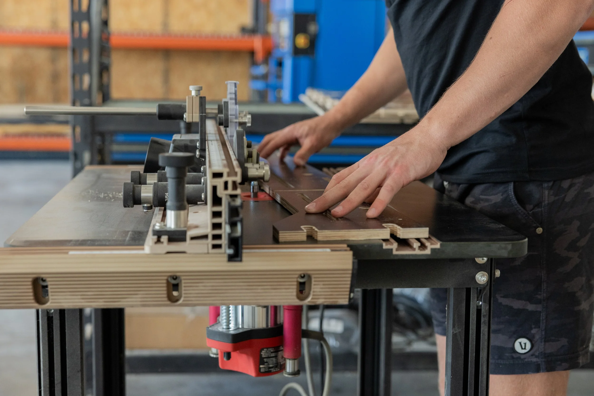 Person working with woodworking machinery in a workshop, routing wood pieces.
