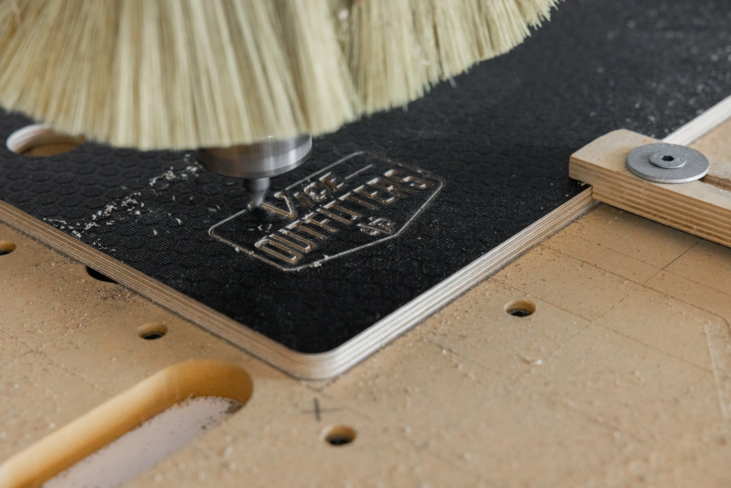 A router bit engraving the VICE Outfitters logo into plywood