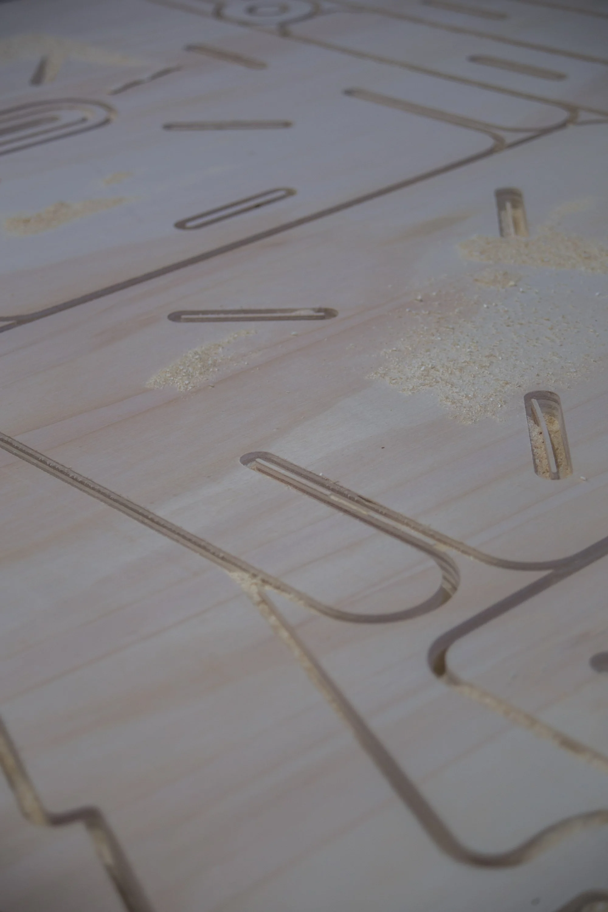 Close-up of a wooden puzzle with engraved lines and scattered sawdust.