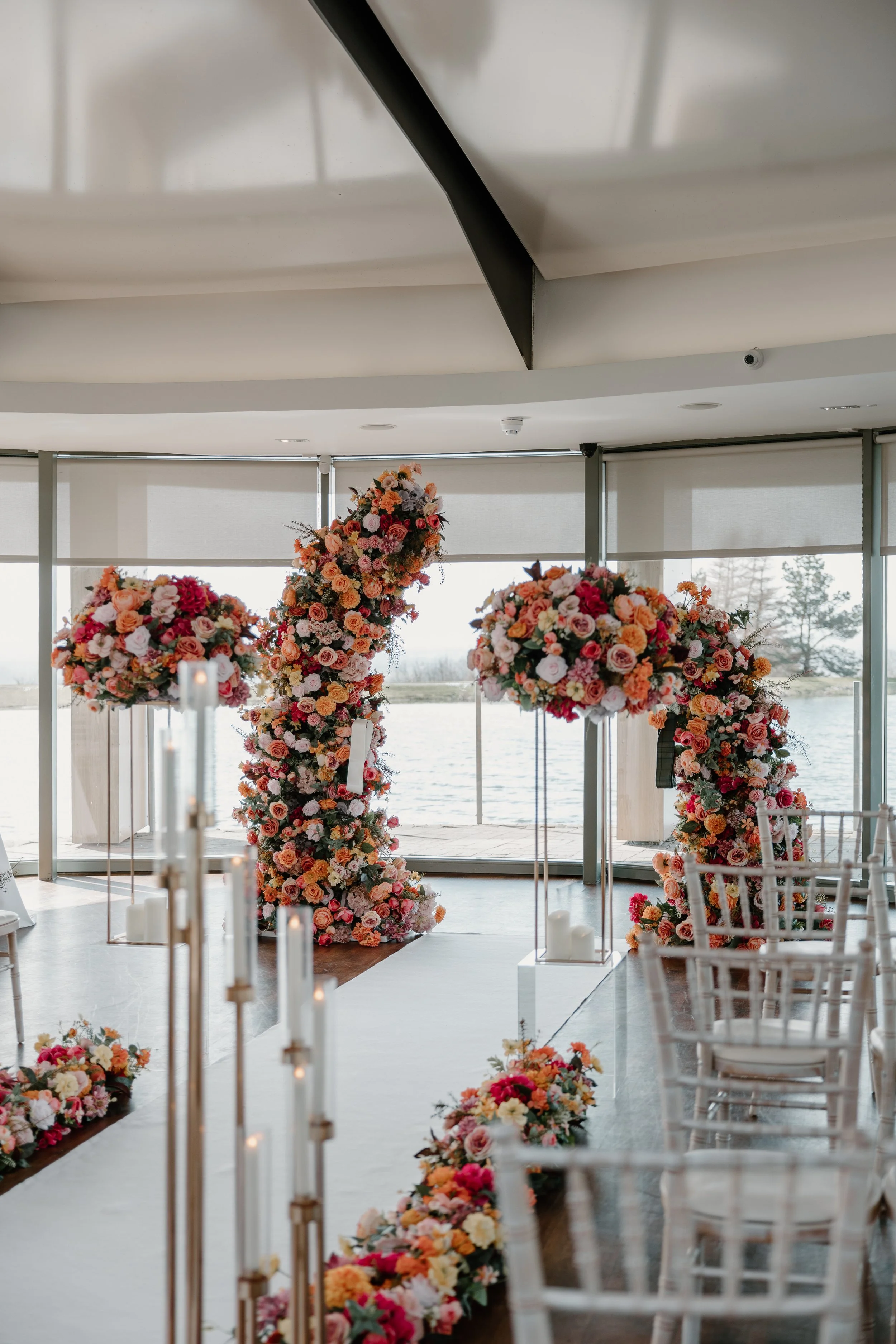 Colourful silk floral split arch with matching flower arrangements for a wedding ceremony