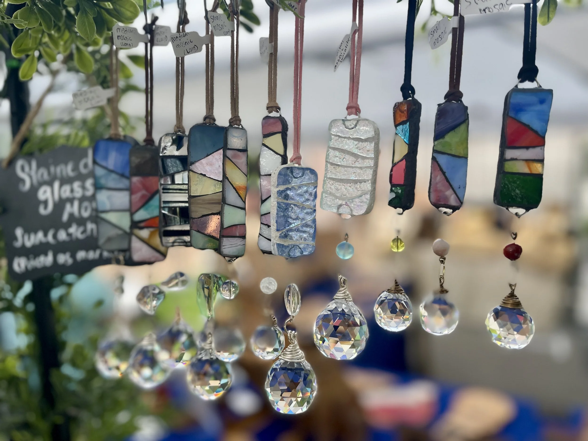 Colorful stained glass mosaic sun catchers and ornaments hanging at a market stall.