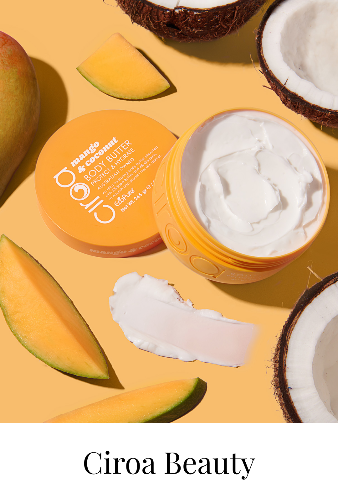 An open container of Ciroa Beauty mango and coconut body butter surrounded by slices of mango and coconut.