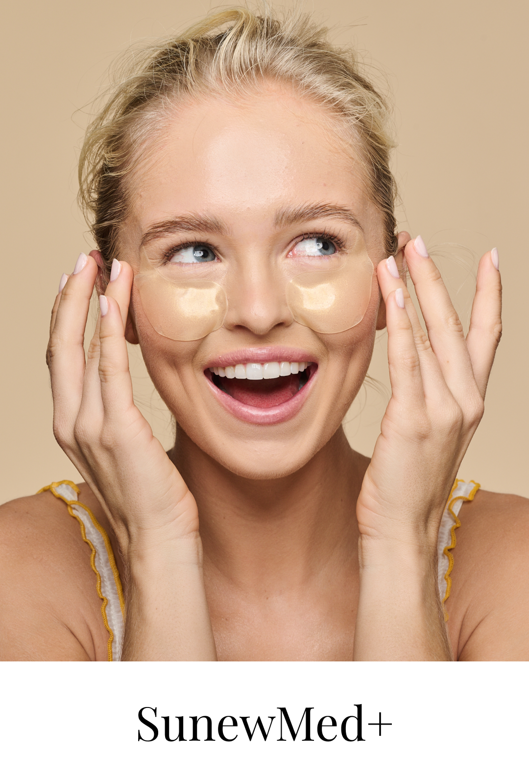 A woman with blonde hair smiling, wearing gold-colored eye patches under her eyes, with her hands near her face, promoting skincare by SunewMed+.