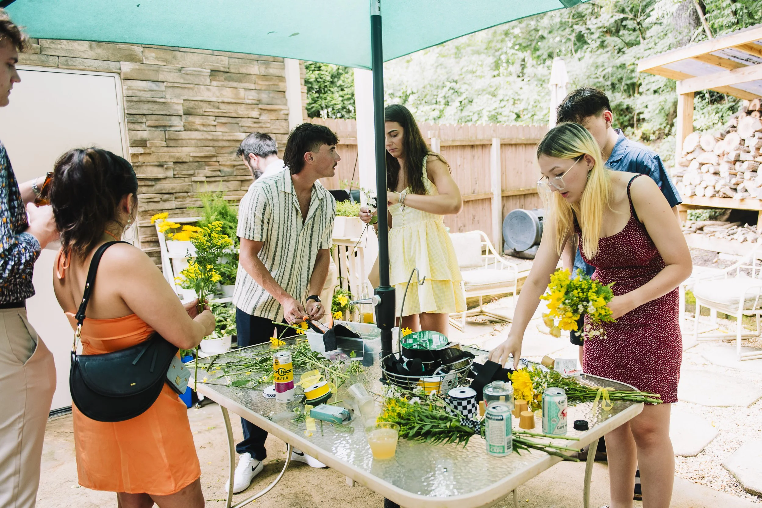 People arranging yellow flowers on a table in a backyard during daytime.