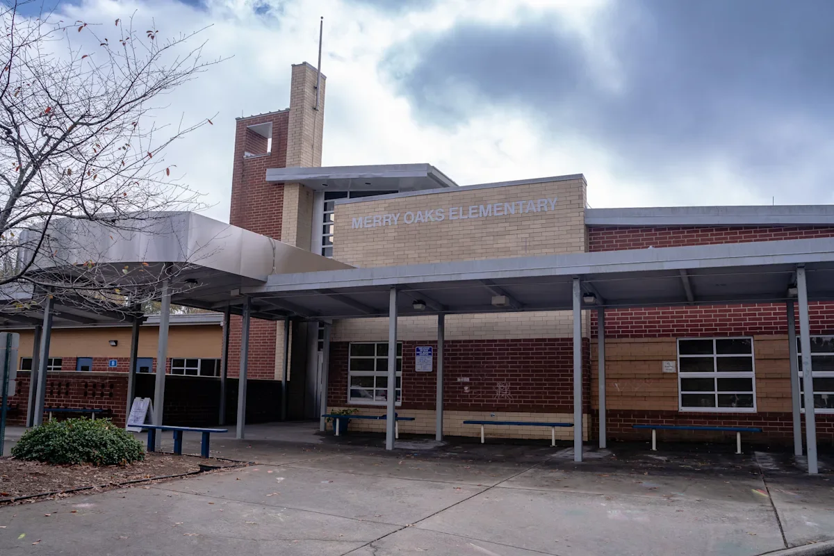 Exterior of Merry Oaks Elementary School with seating area and leafless tree in front.