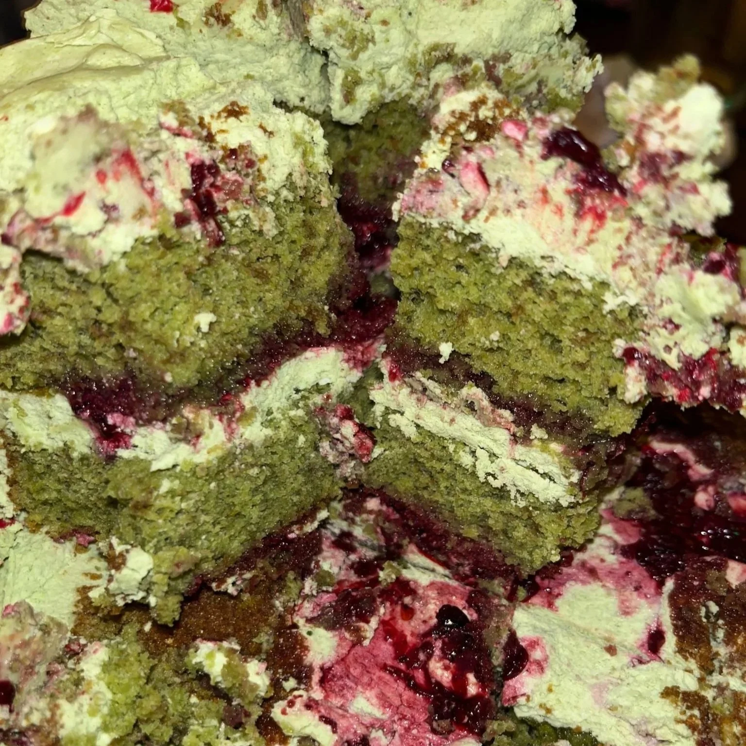 Close-up of a layered cake with matcha sponge layers, matcha buttercream, and blackberry jam.