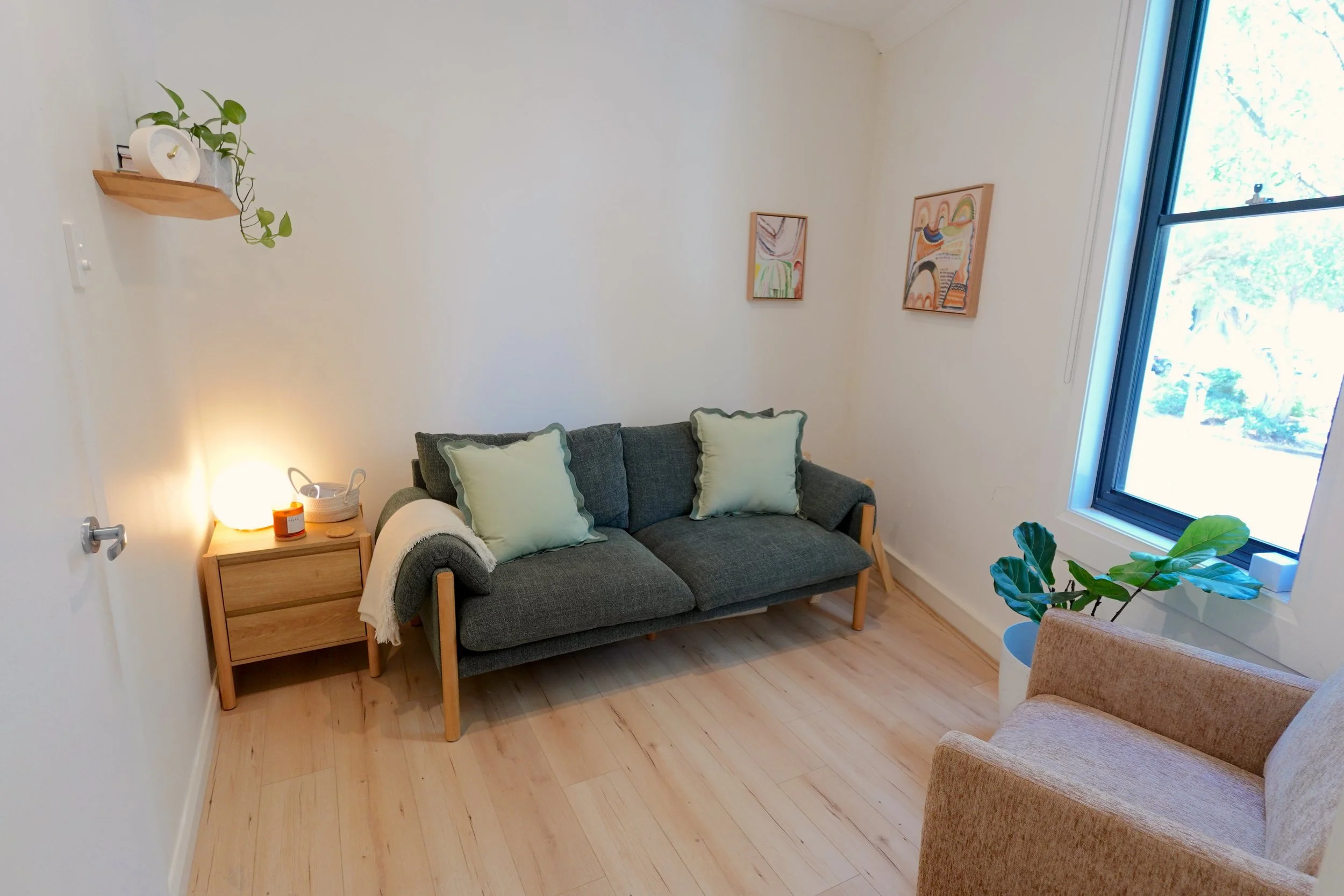 Two pale yellow poppy flowers with dark centers and crinkled petals in a vase against a light, semi-transparent curtain.