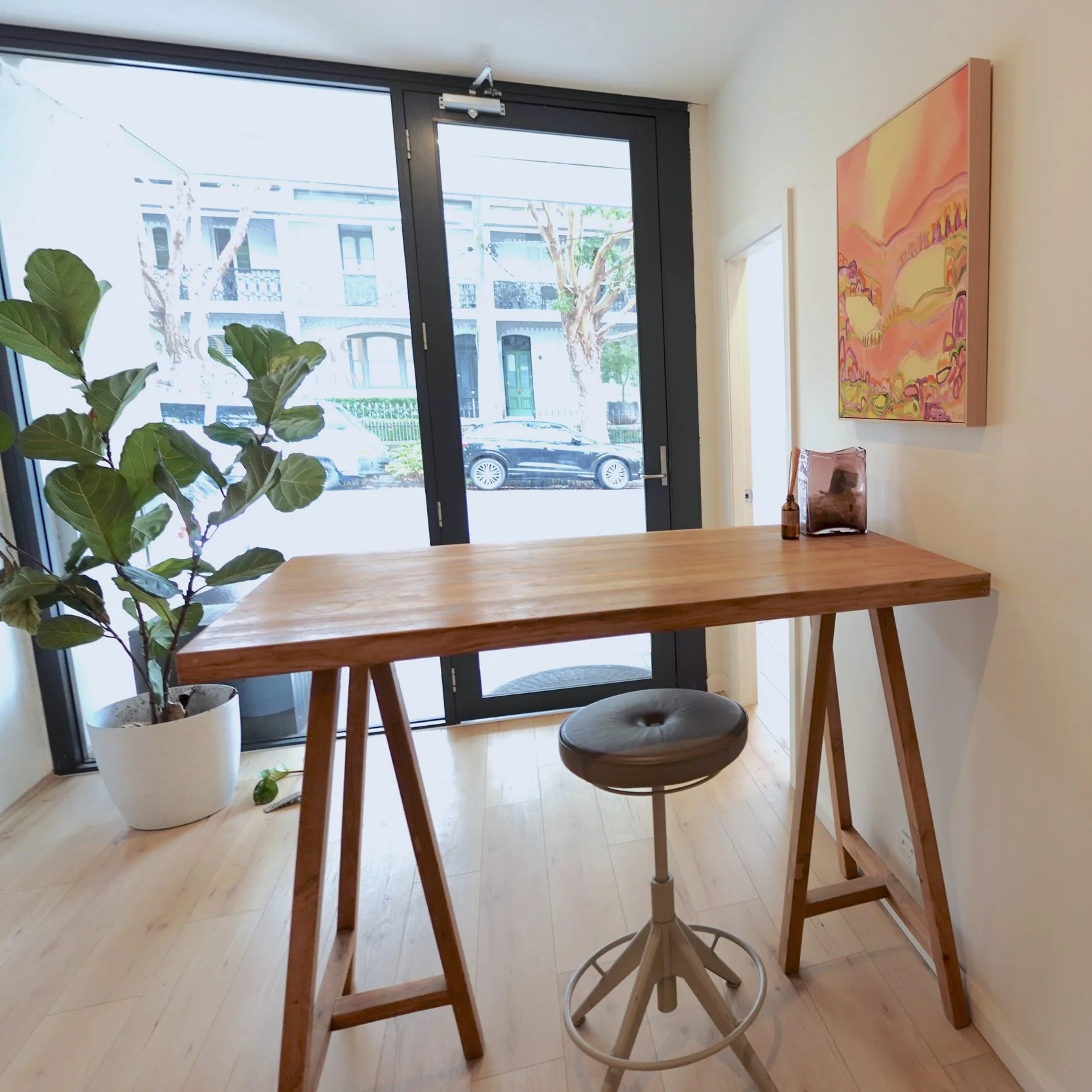 Two pale yellow poppy flowers with dark centers and crinkled petals in a vase against a light, semi-transparent curtain.