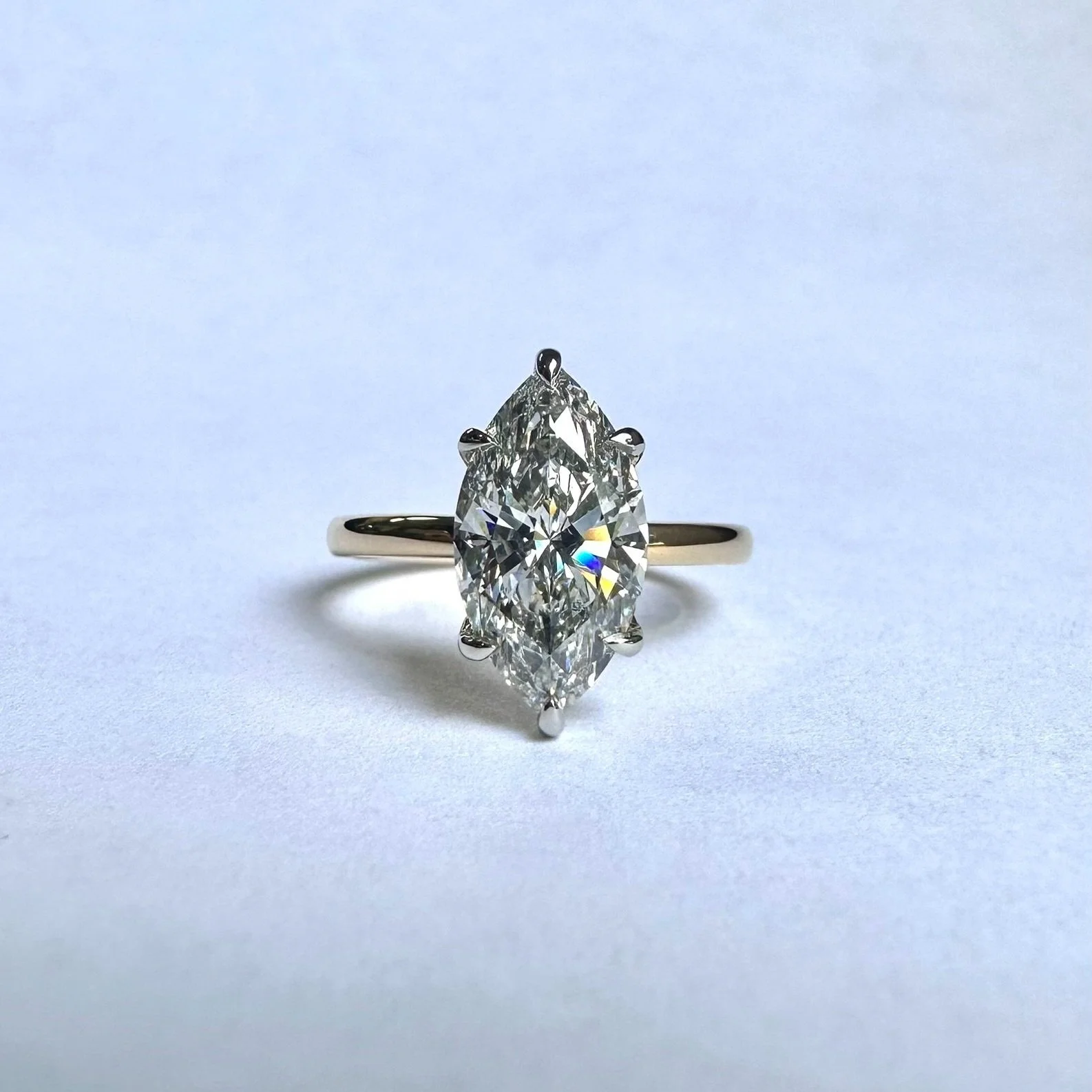 A diamond engagement ring with a marquise-cut diamond set in a four-prong setting on a white background.