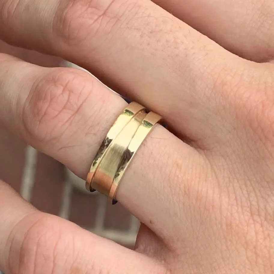 Close-up of a hand wearing two gold wedding bands on the ring finger.
