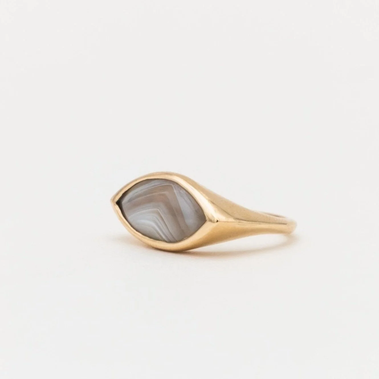 Gold ring with an oval gray and white striped stone set in the center