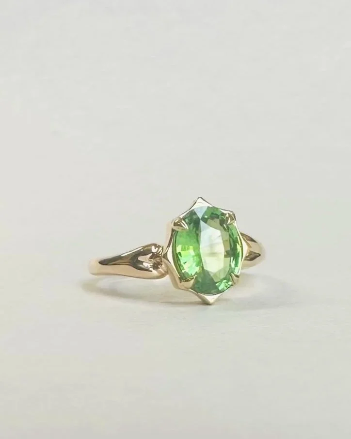 Gold ring with a large oval green gemstone.
