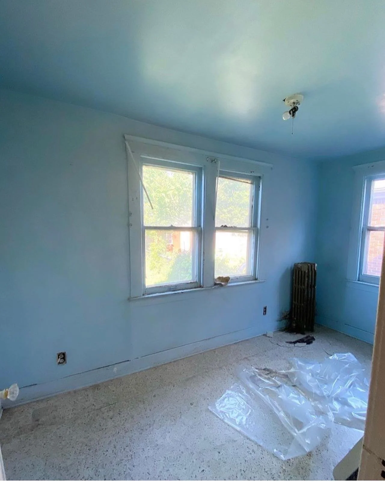 A room with blue walls, a blue ceiling, a window and vinyl floors.