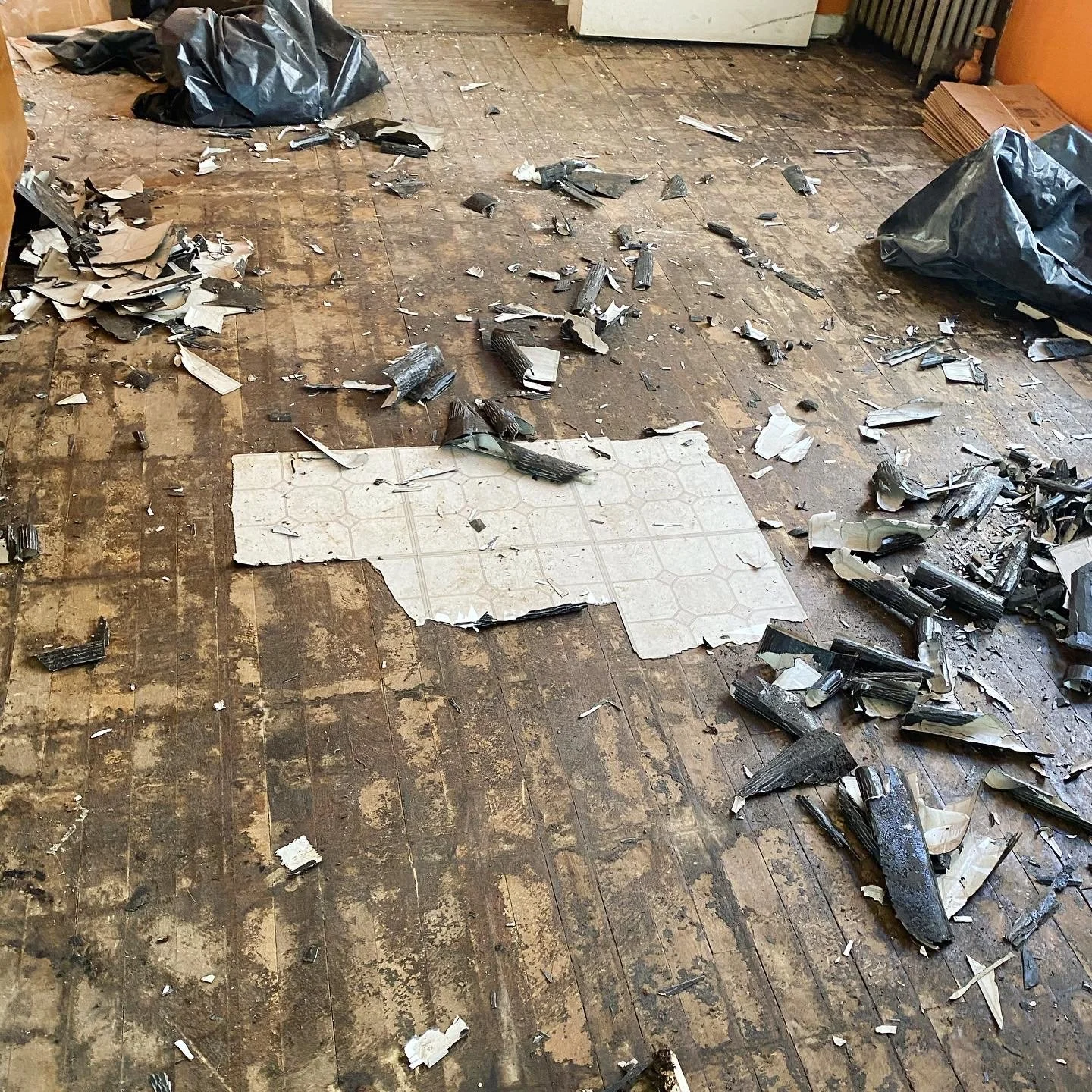 Damaged wood floor with part of the vinyl torn up. 