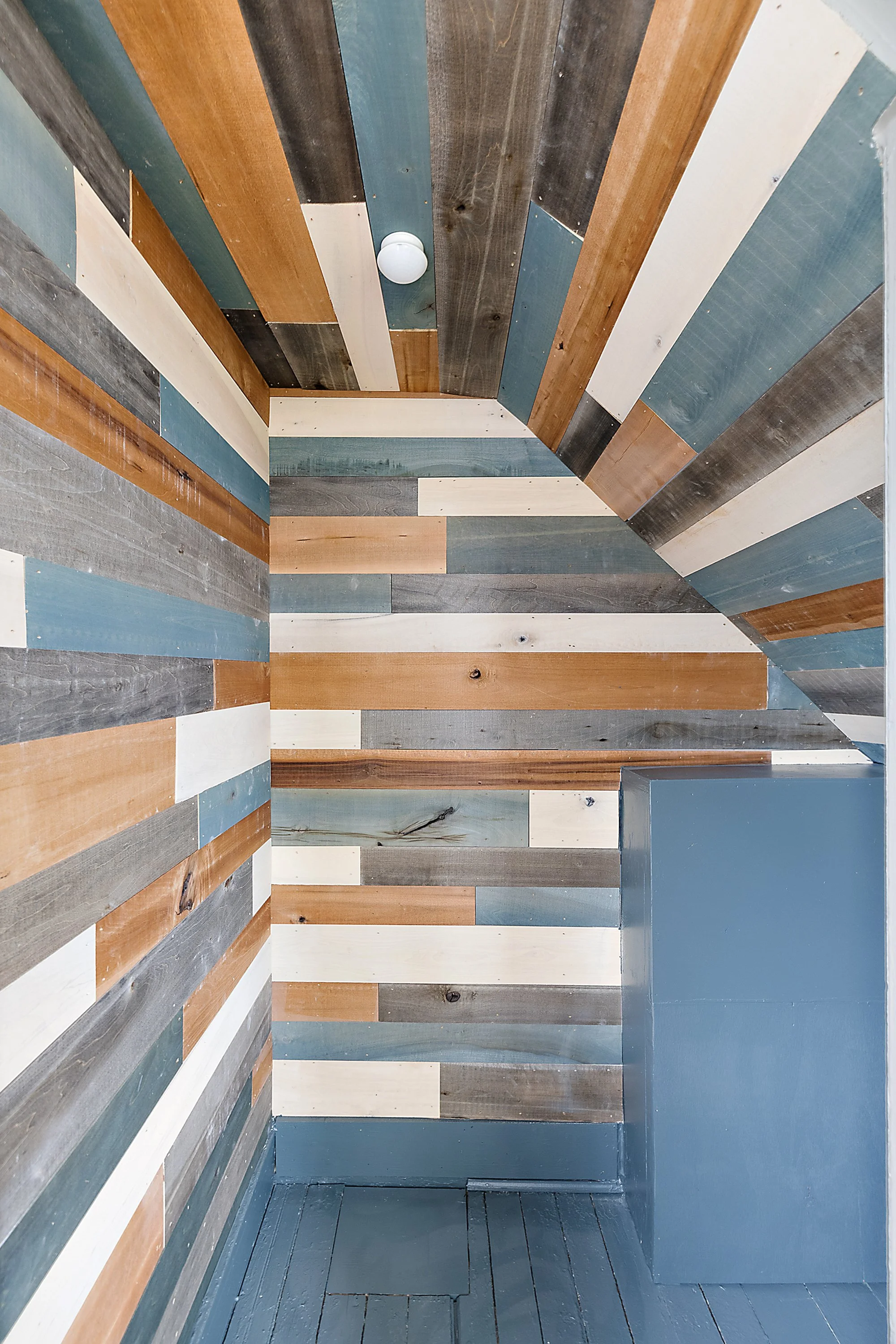 Refinished closet with multi colored wood paneling. 