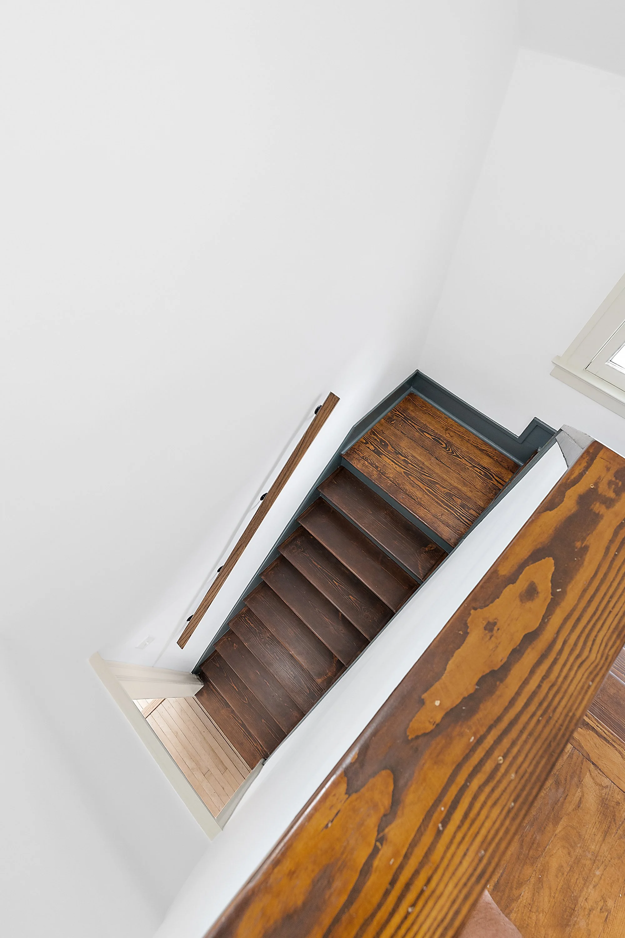 Restored stairwell with wood treads and white plaster walls. 