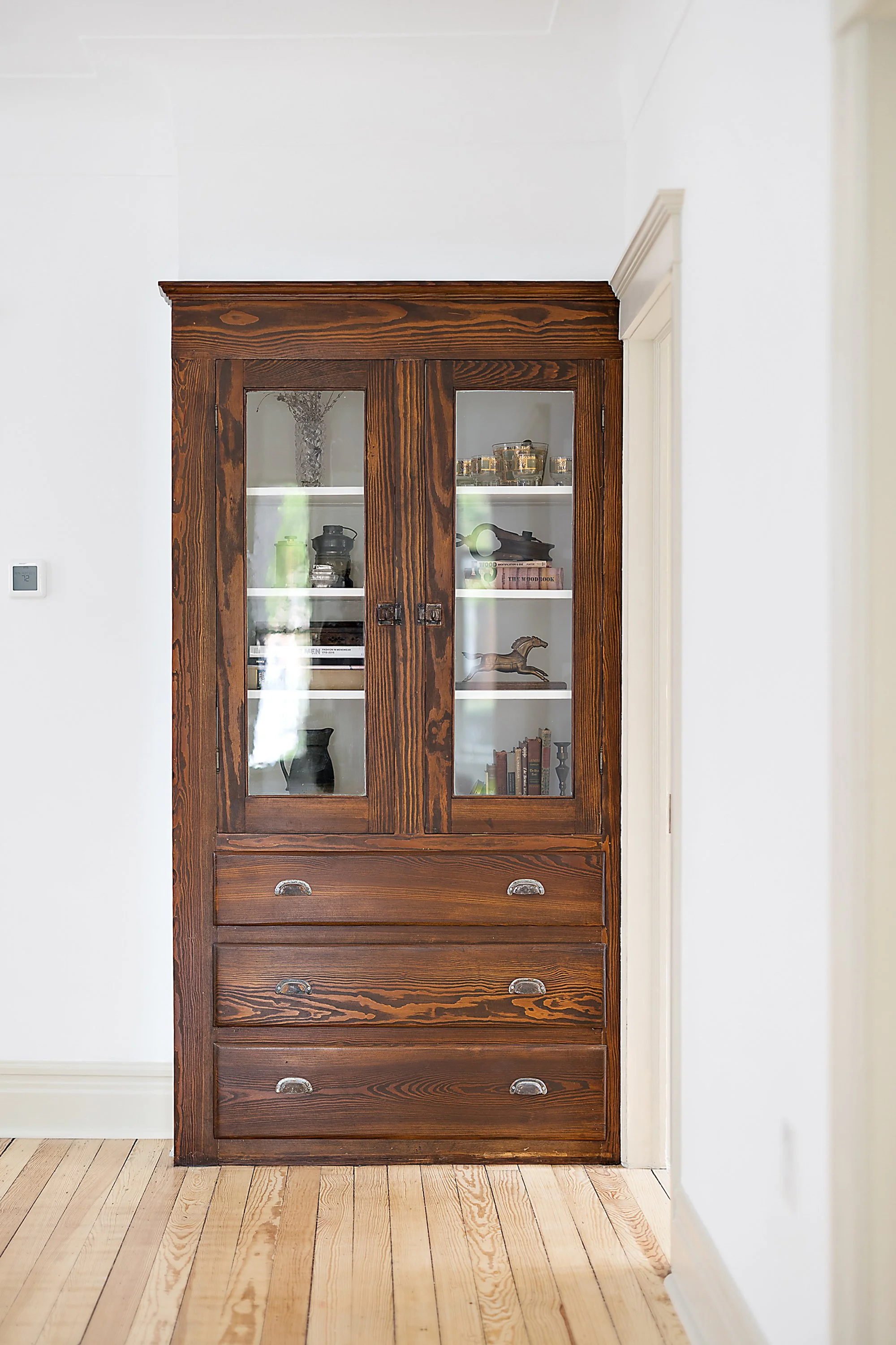 Restored built in cabinet that was stripped of paint and stained. Cabinet includes home decor inside of it. 