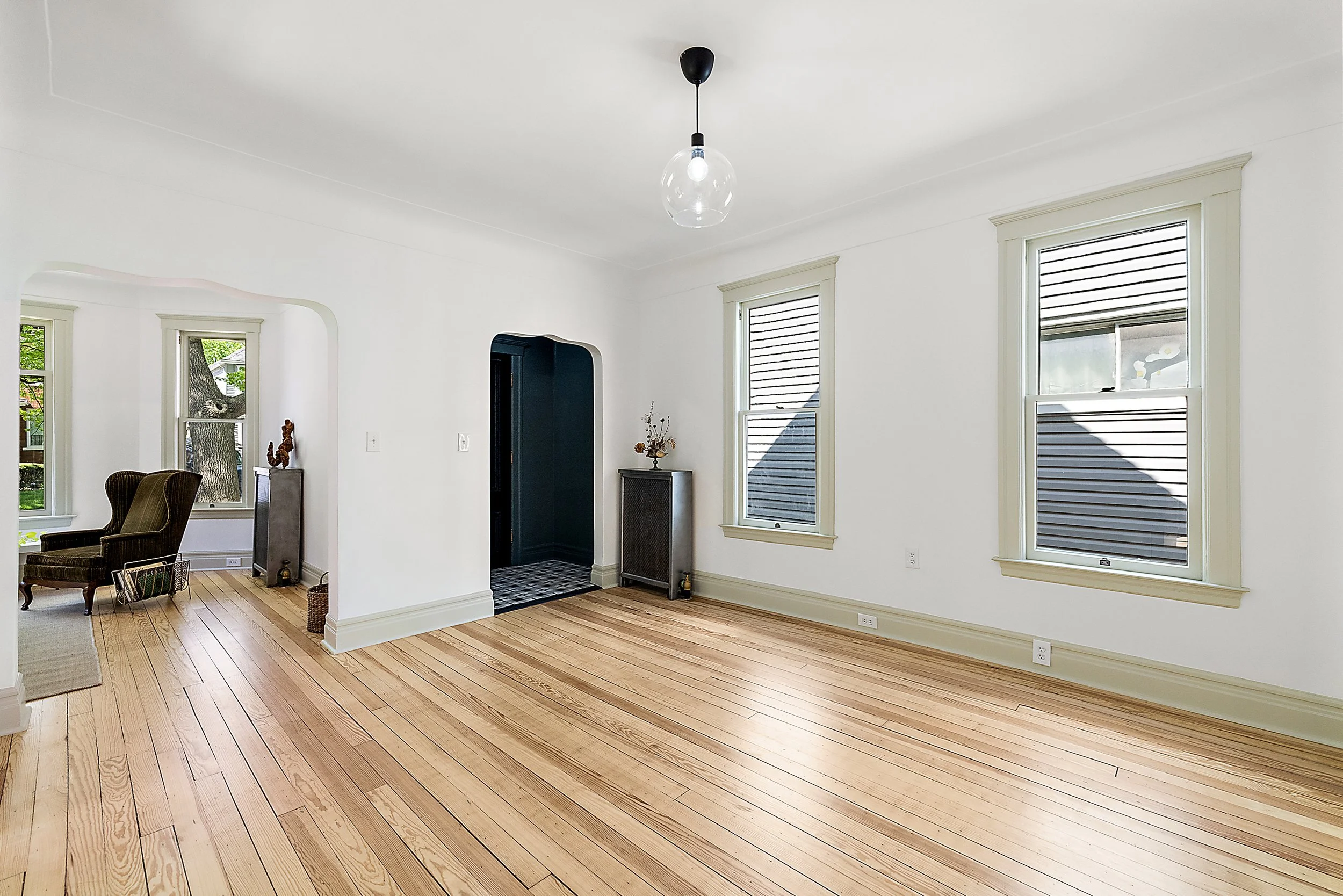 Restored front room with pine floors, white walls, green trim, and green entry way. 