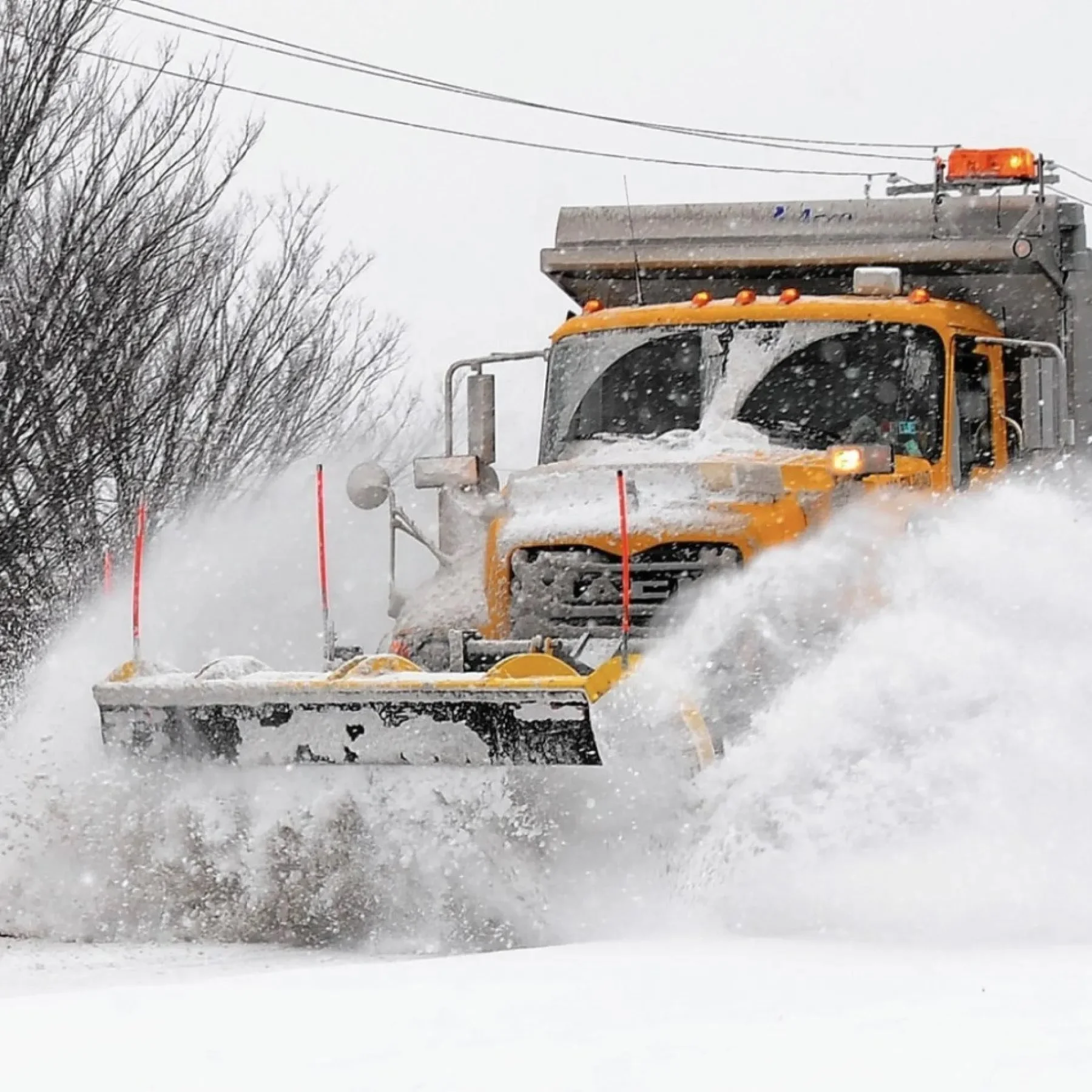 A snow plow clearing snow from the road during a snowstorm.