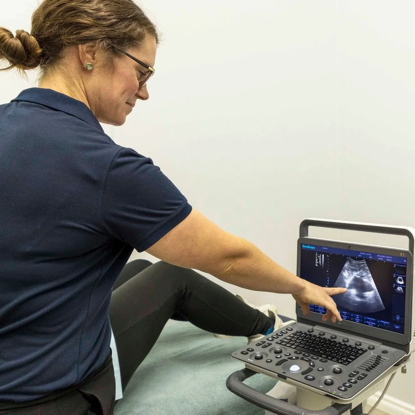 A healthcare professional demonstrating an ultrasound scan on a computer screen.
