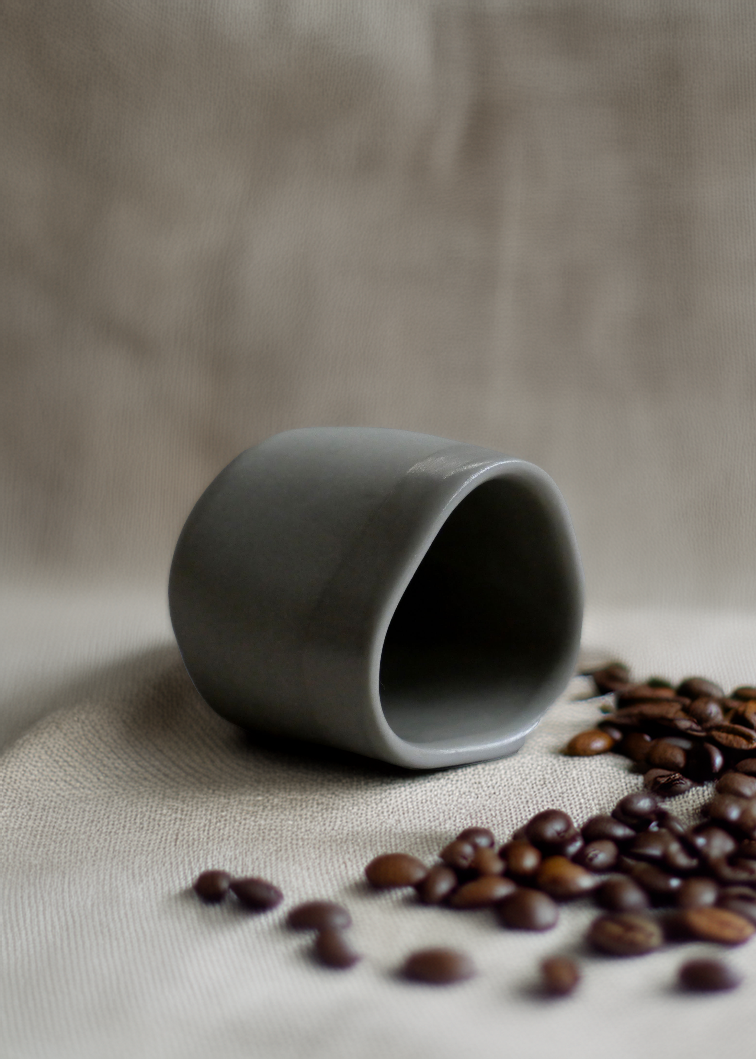 A Geometric espresso cup laying on its side to show of its soft triangular shape by morph and mould