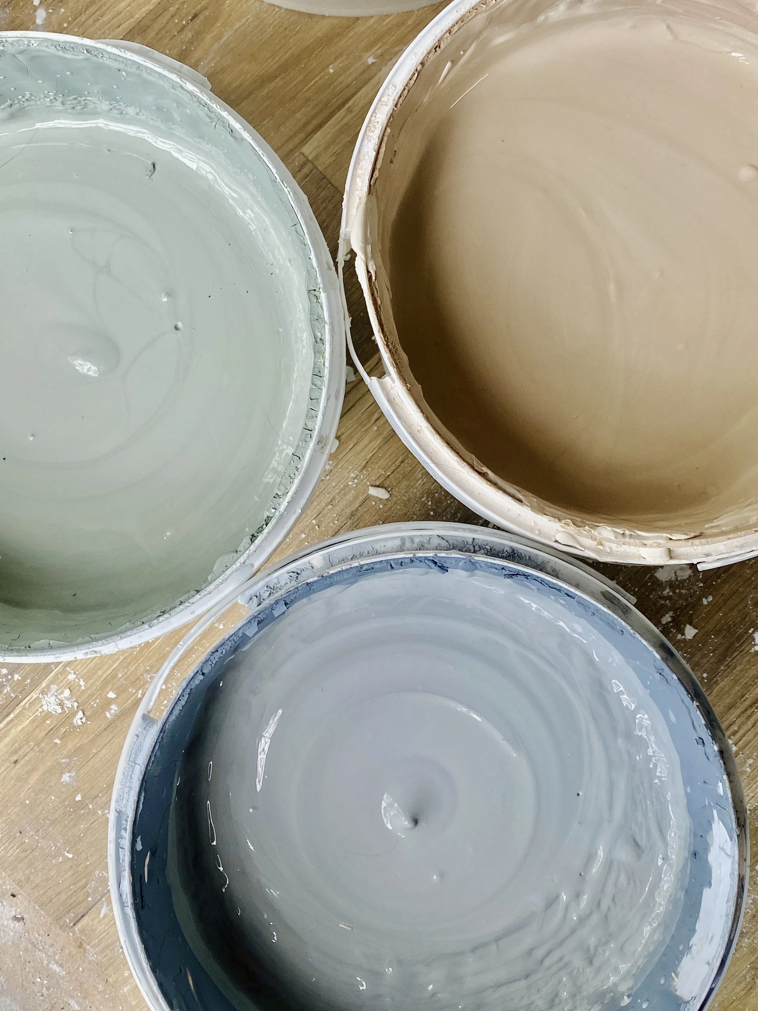 Three buckets of mixed slip, one green, one grey and the other orange