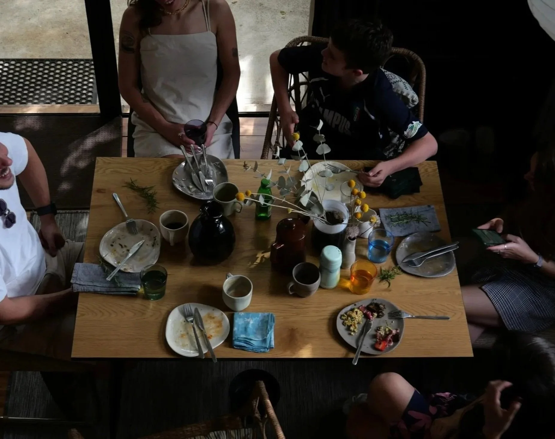 A home bruch with friends. A shot taken from above. A wooden Table set with morph and moulds side plate, organic mugs and bud vase. Glass cups and glass vase. Billy buttons in vases. In an Adelaide home