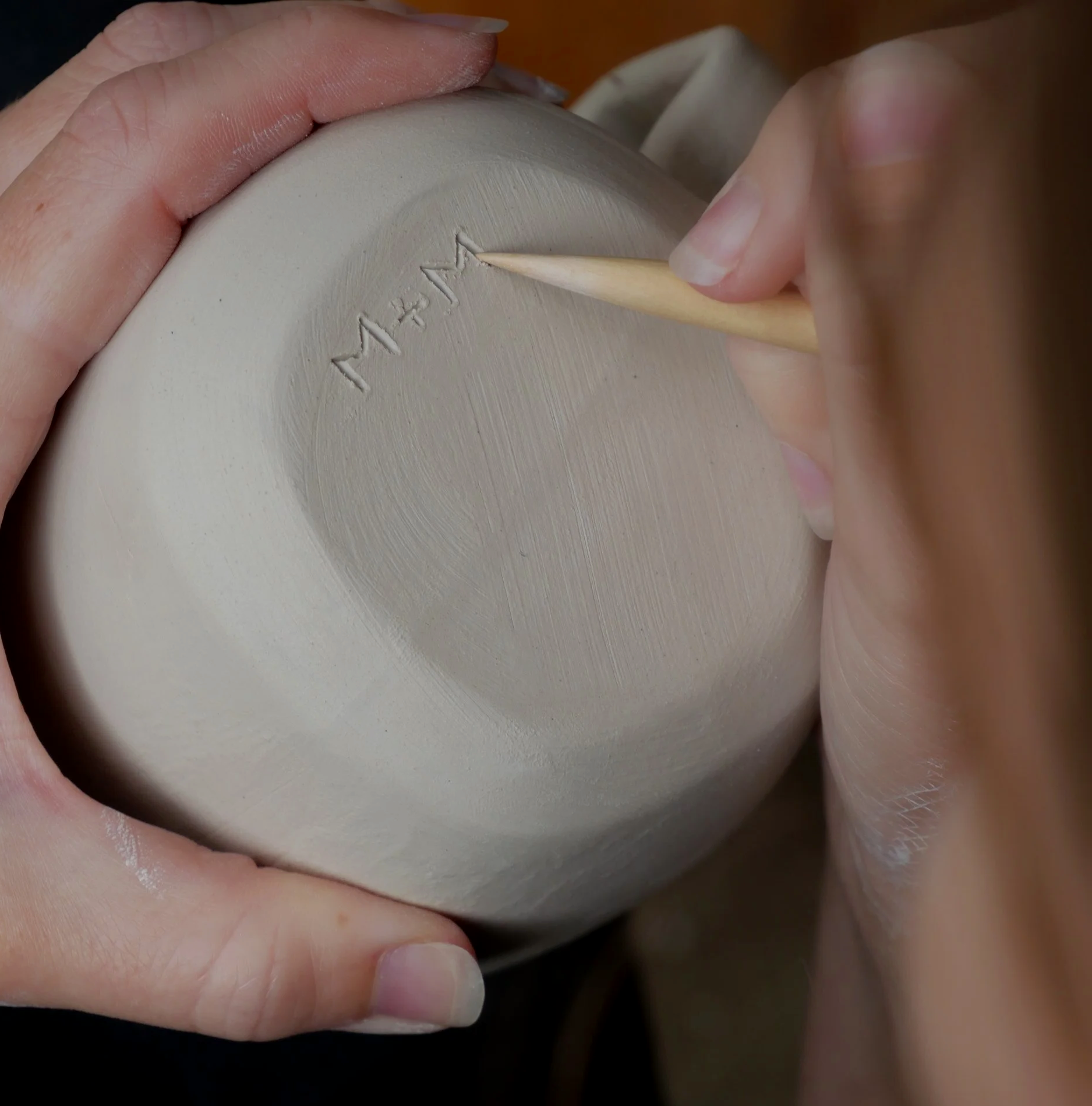 Deanna’s hand scribing the M+M maker’s mark into the base of a porcelain cup