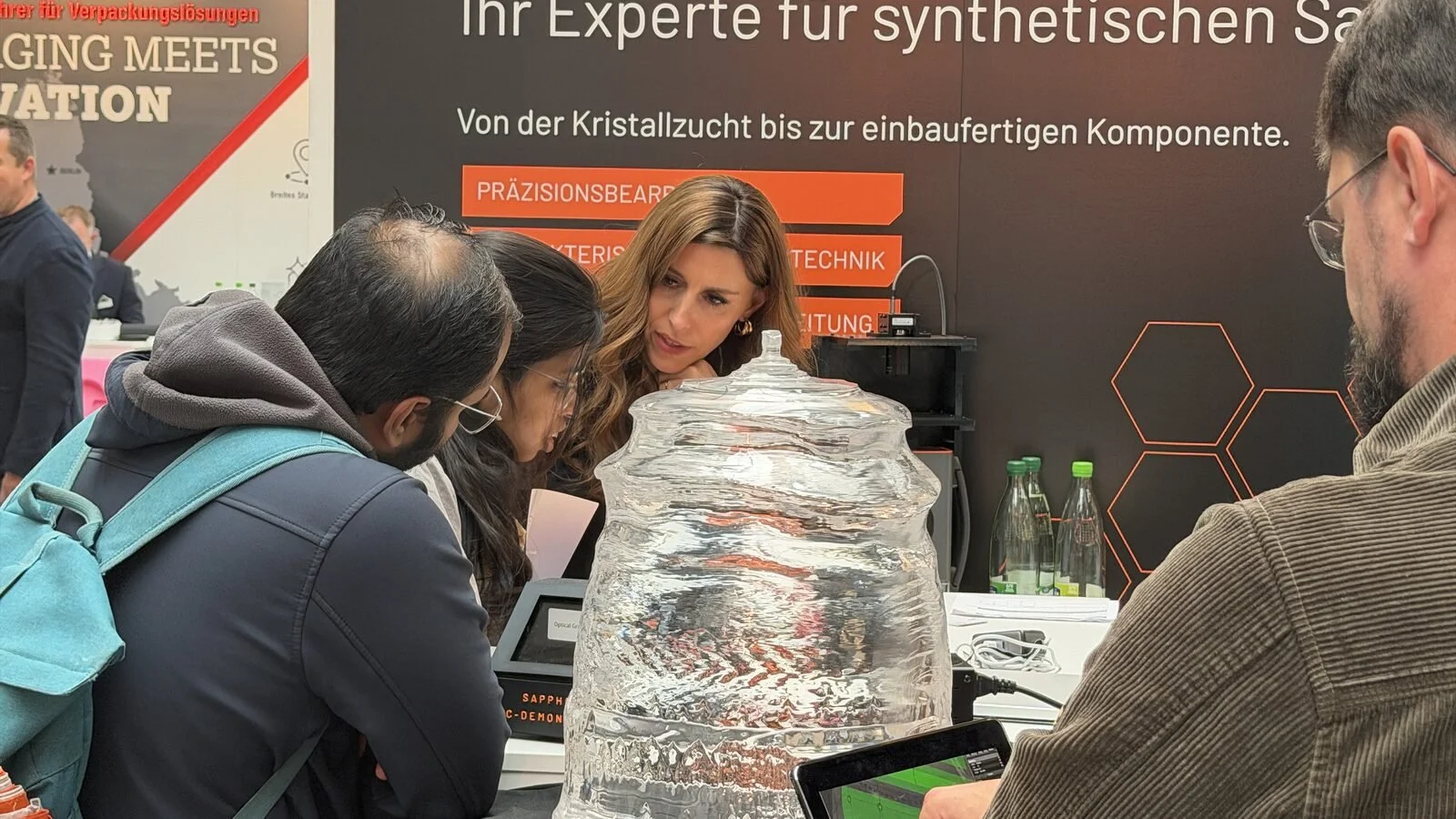 Trade-fair visitors examine the crystal up close and discuss how large sapphire boules become finished components.
