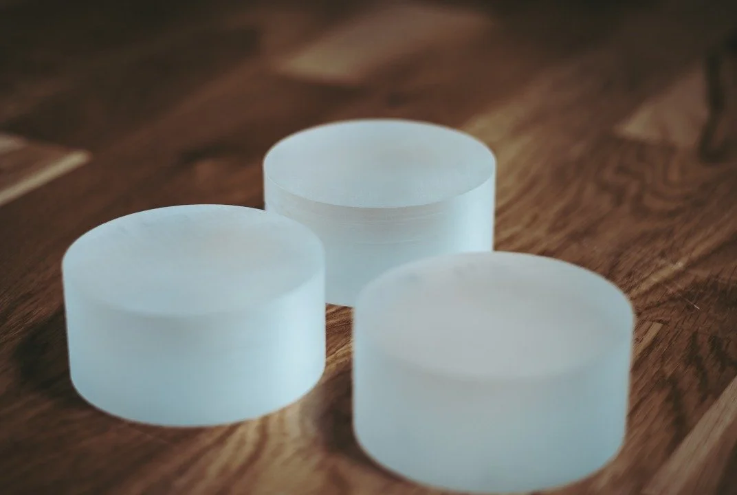Three cylindrical white wax melts on a wooden surface.