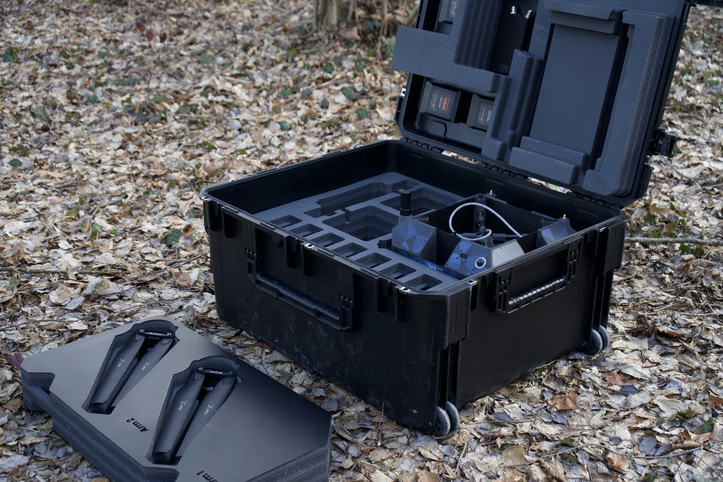 HCI Transport Case With drone, batteries, controller and datalinks inside the case and arms with propellors on ground in inlay.
