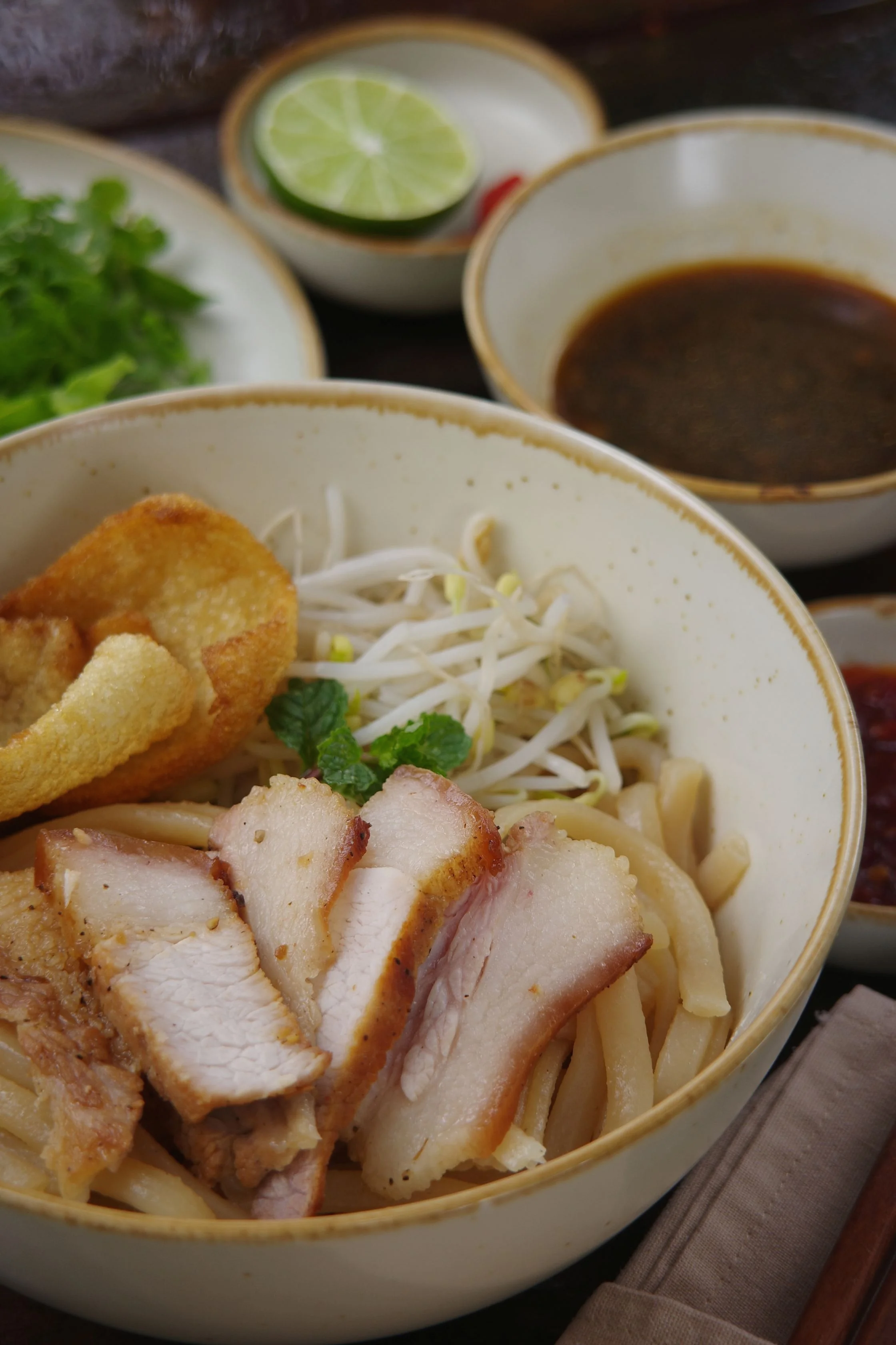 Cao lau noodle dish with char siu and fresh herbs

