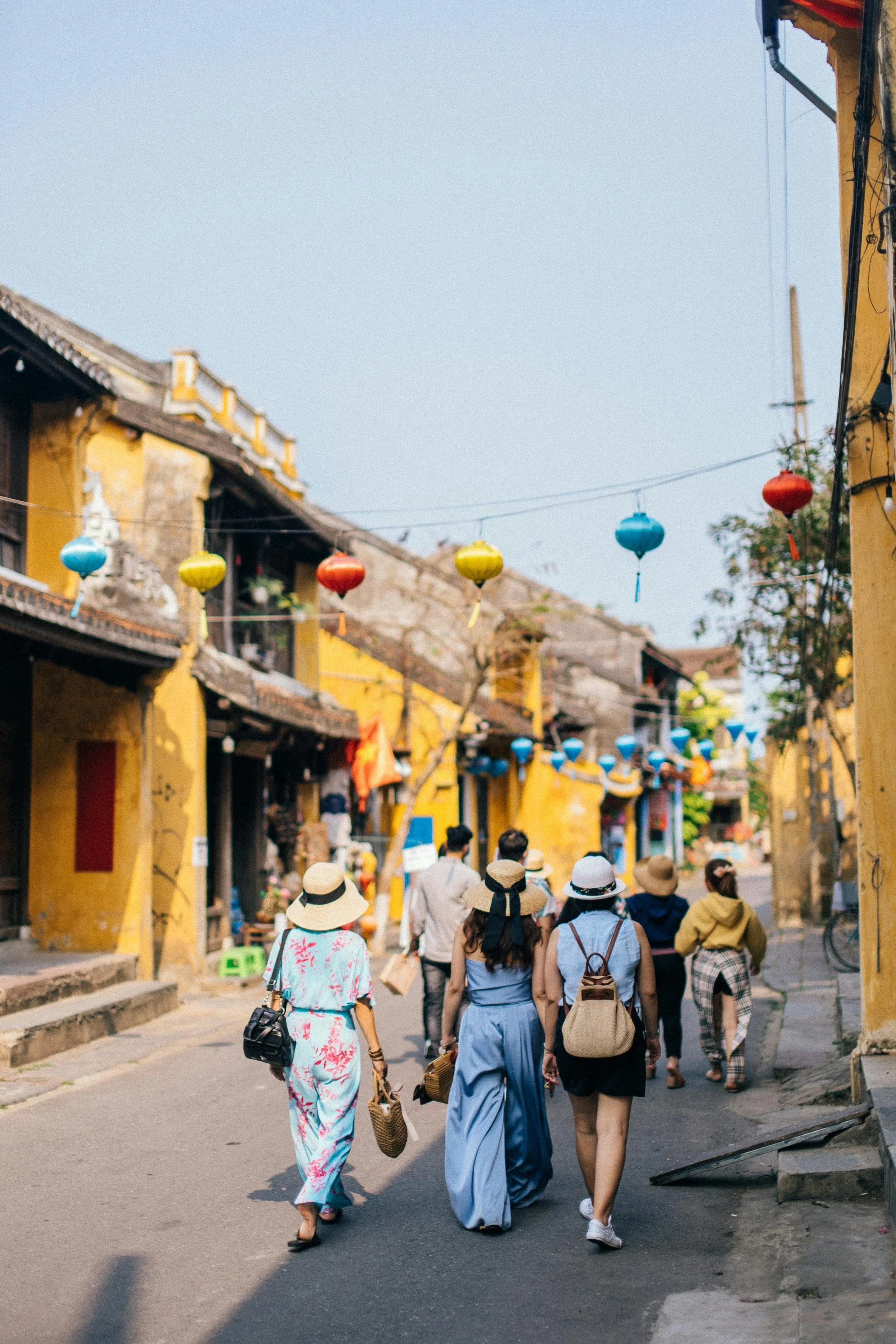 Visitors strolling through Hoi An's old town under colorful silk lanterns and yellow heritage buildings