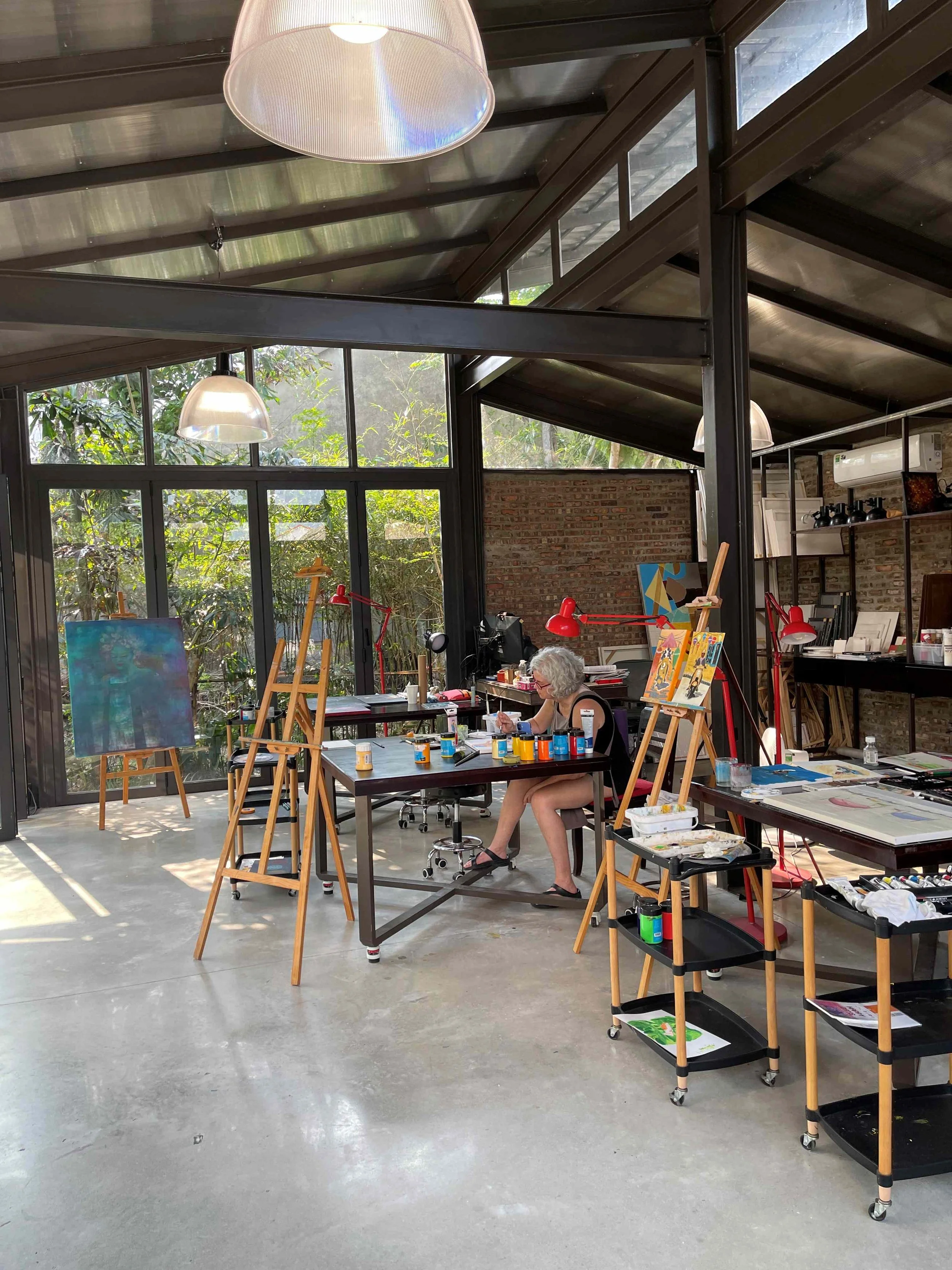 Guest creating art in the studio of The Interlude sitting at a table surrounded by easels and art supplies