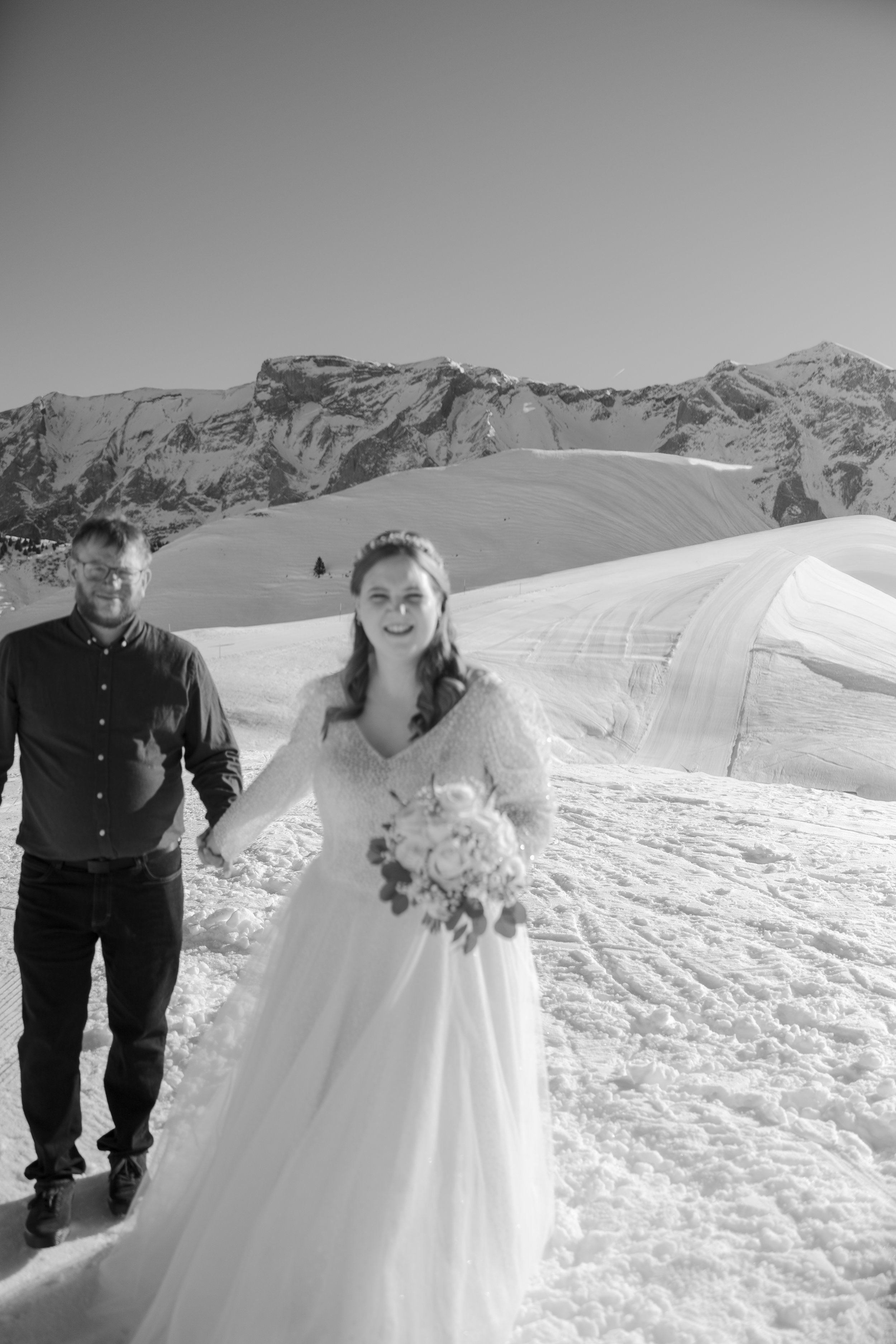 Braut und Bräutigam auf Schneefeld mit Bergen im Hintergrund