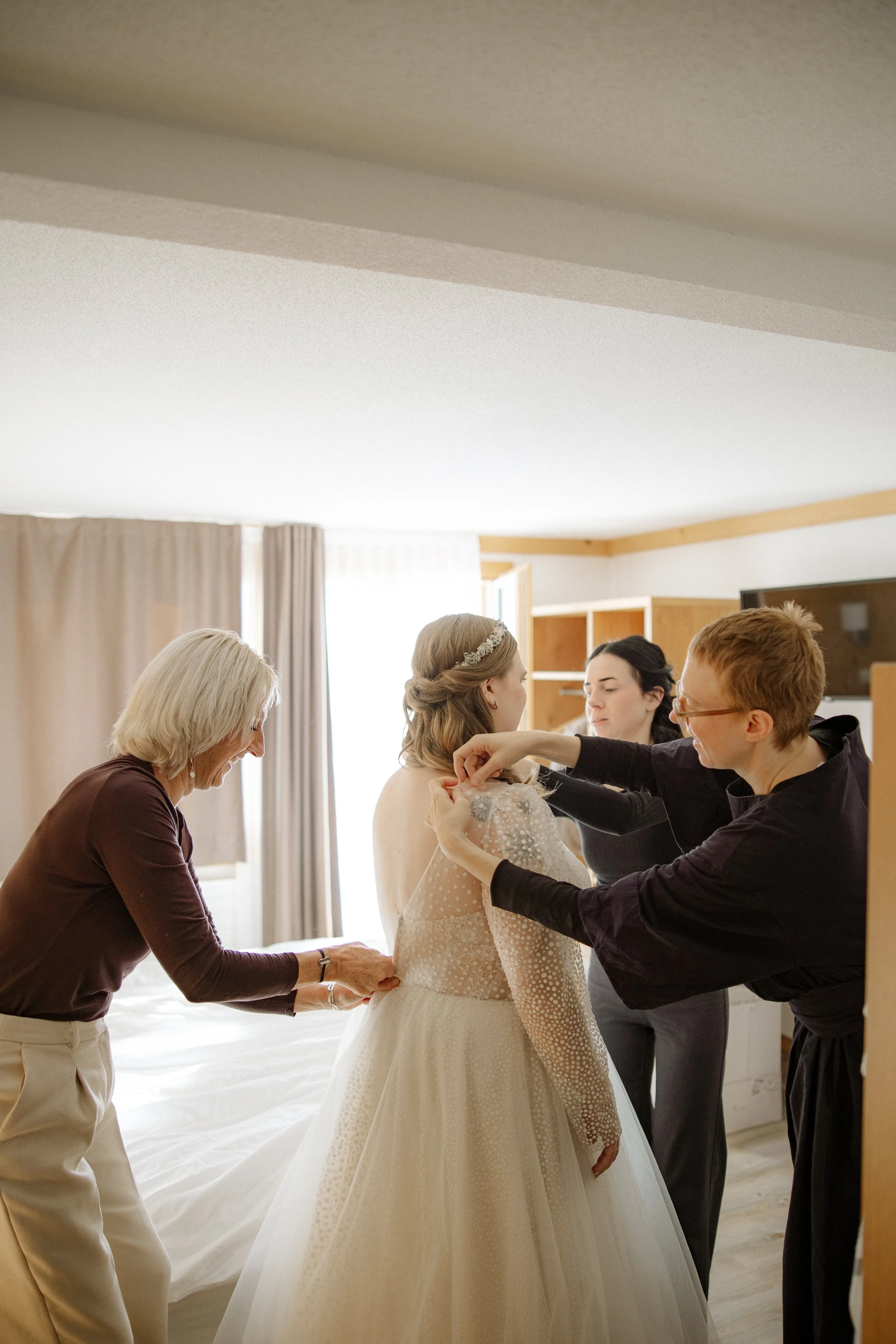 Menschen beim Ankleiden einer Braut in einem Hotelzimmer.