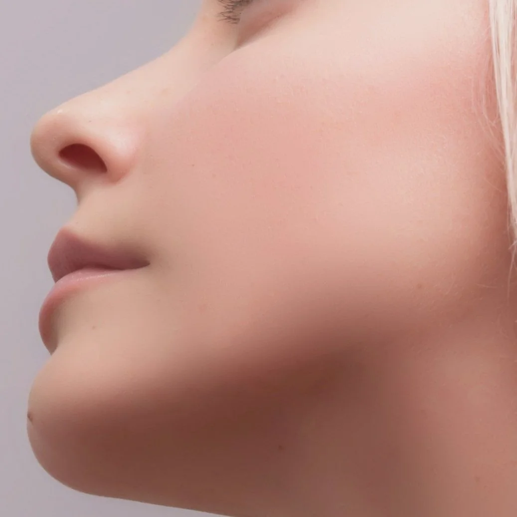 Close-up profile of a woman's face showing smooth, clear skin, a defined nose, and closed lips.