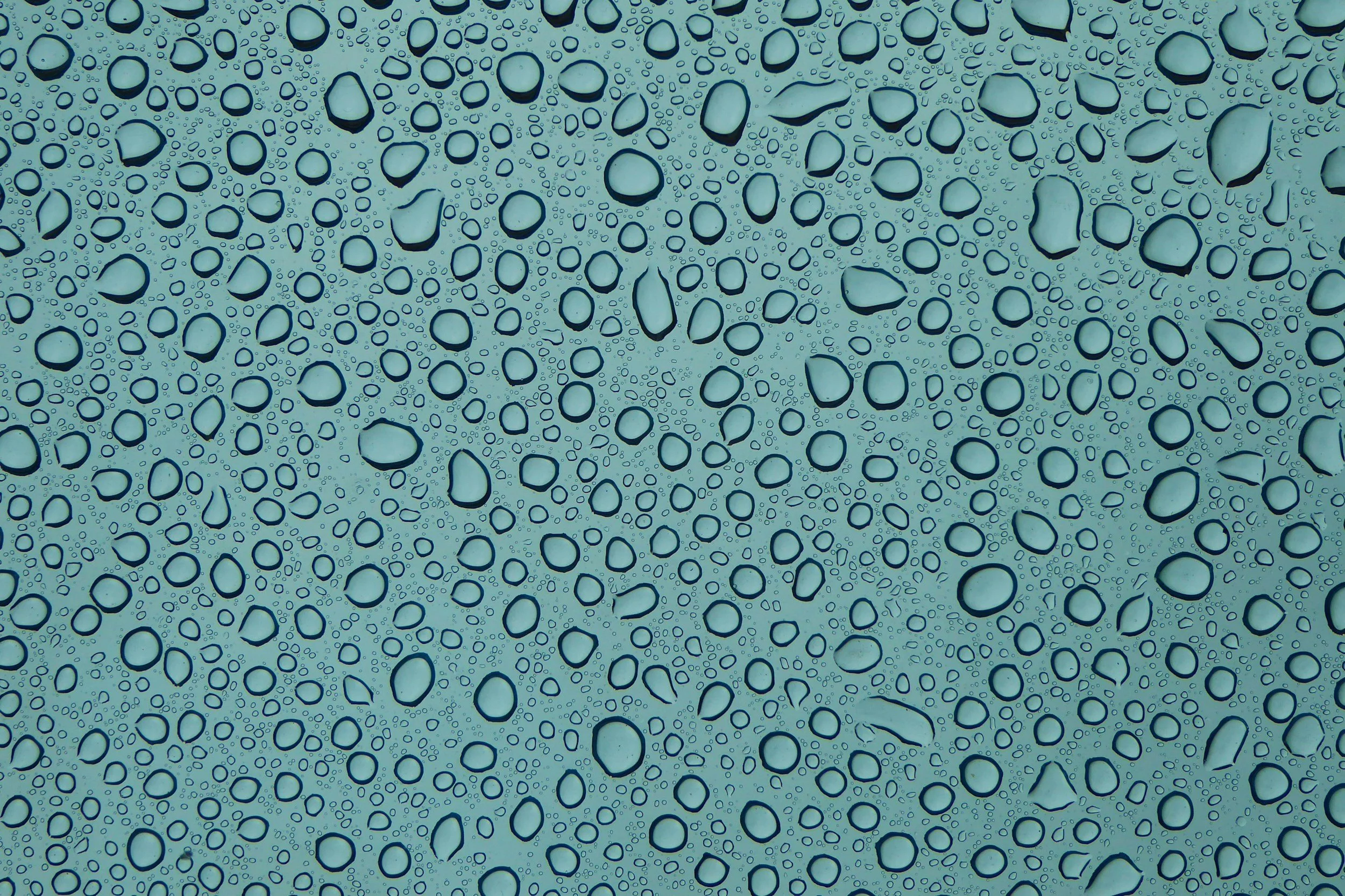 Close-up of water droplets on a glass surface, with a blue background.