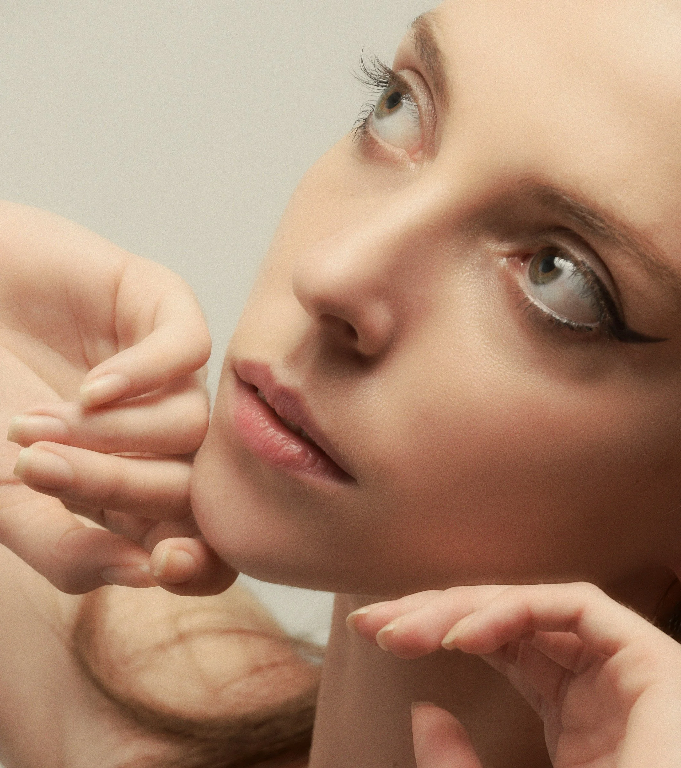 Close-up of a person's face, showing their eye, nose, and part of their mouth, with their hand near their face.