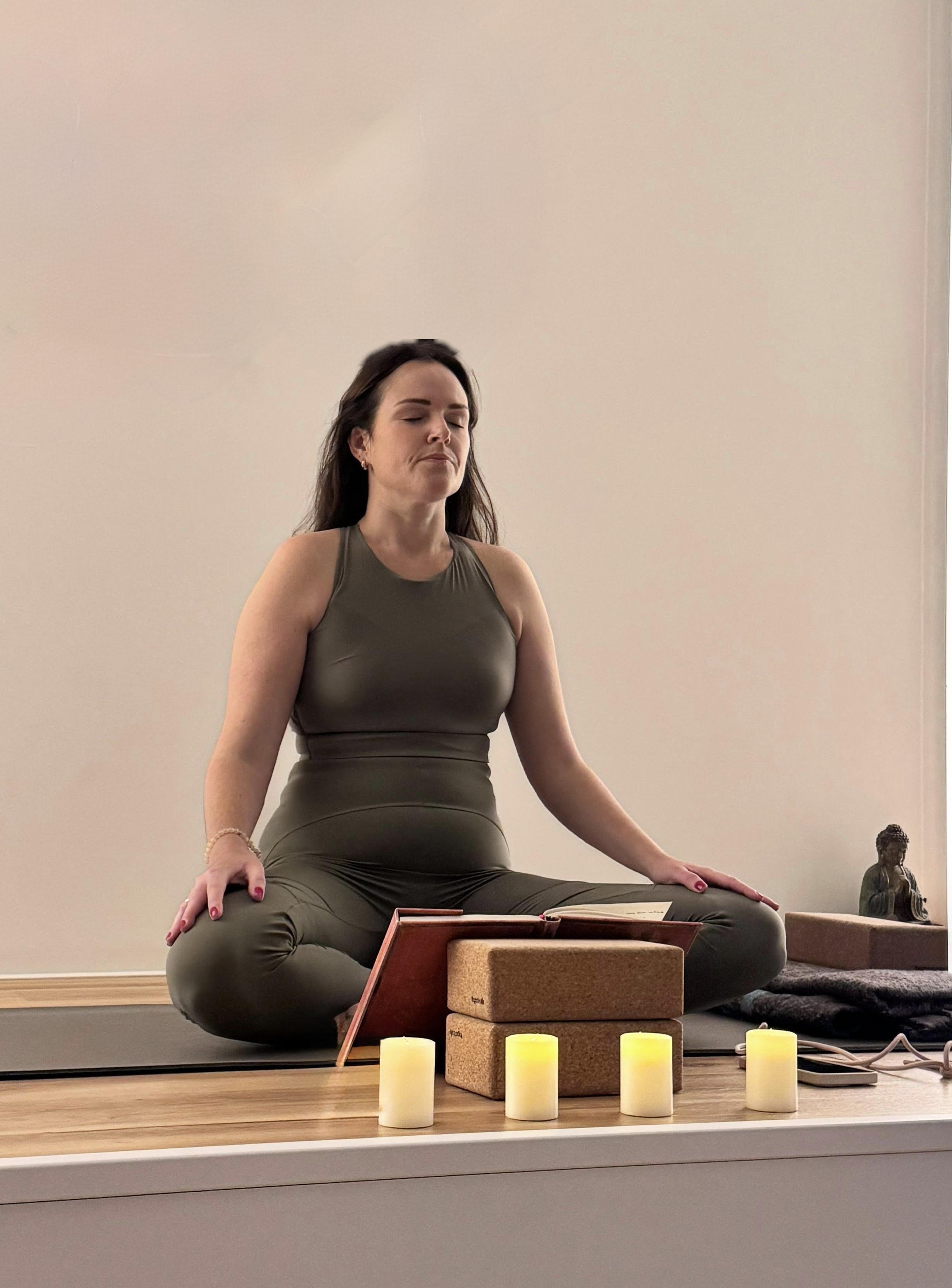 Una mujer haciendo yoga en un pasillo entre barriles de vino de madera en un ambiente rústico.